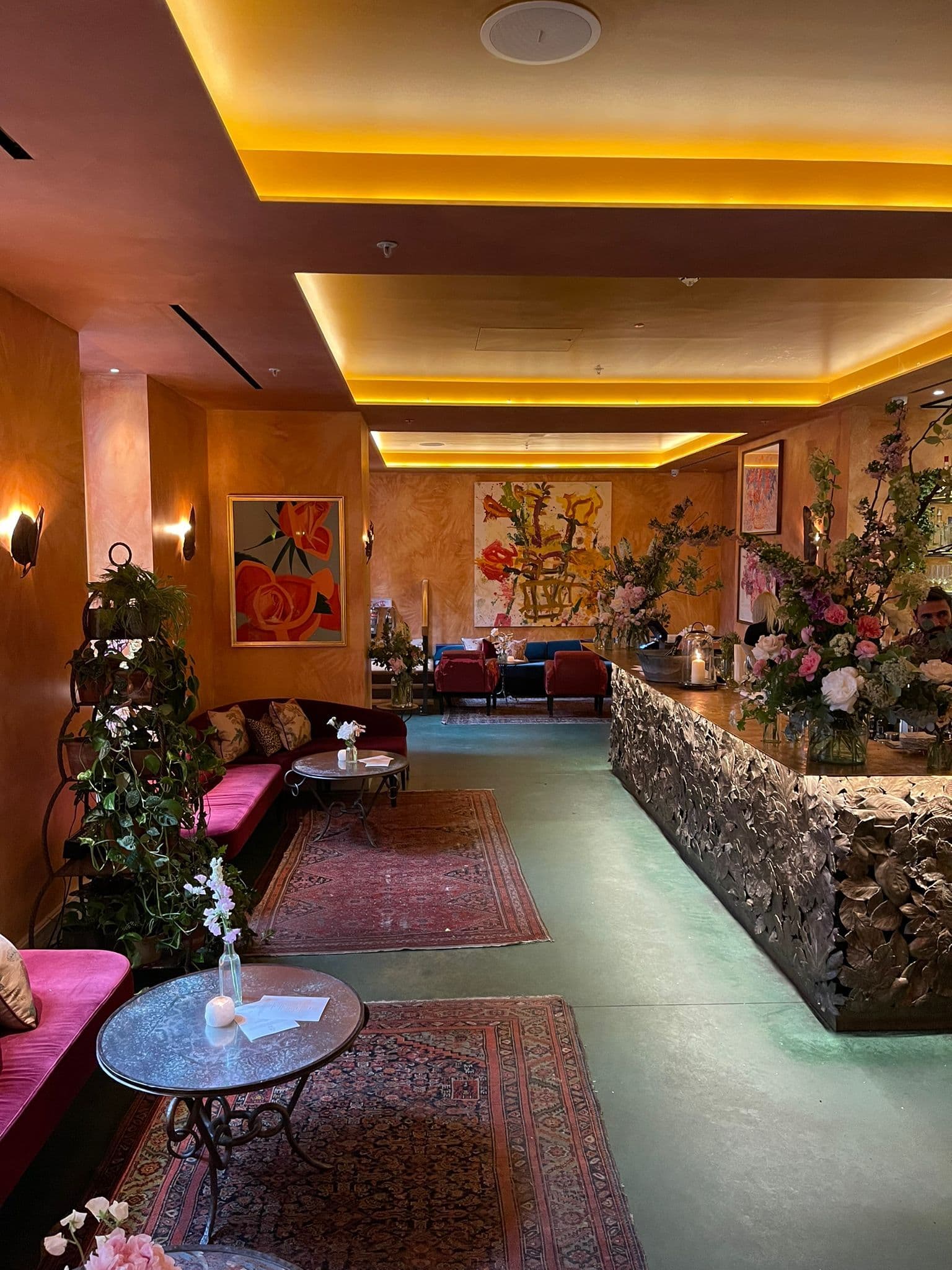 Stylish event space at La Goccia, featuring warm orange walls and floral decor.