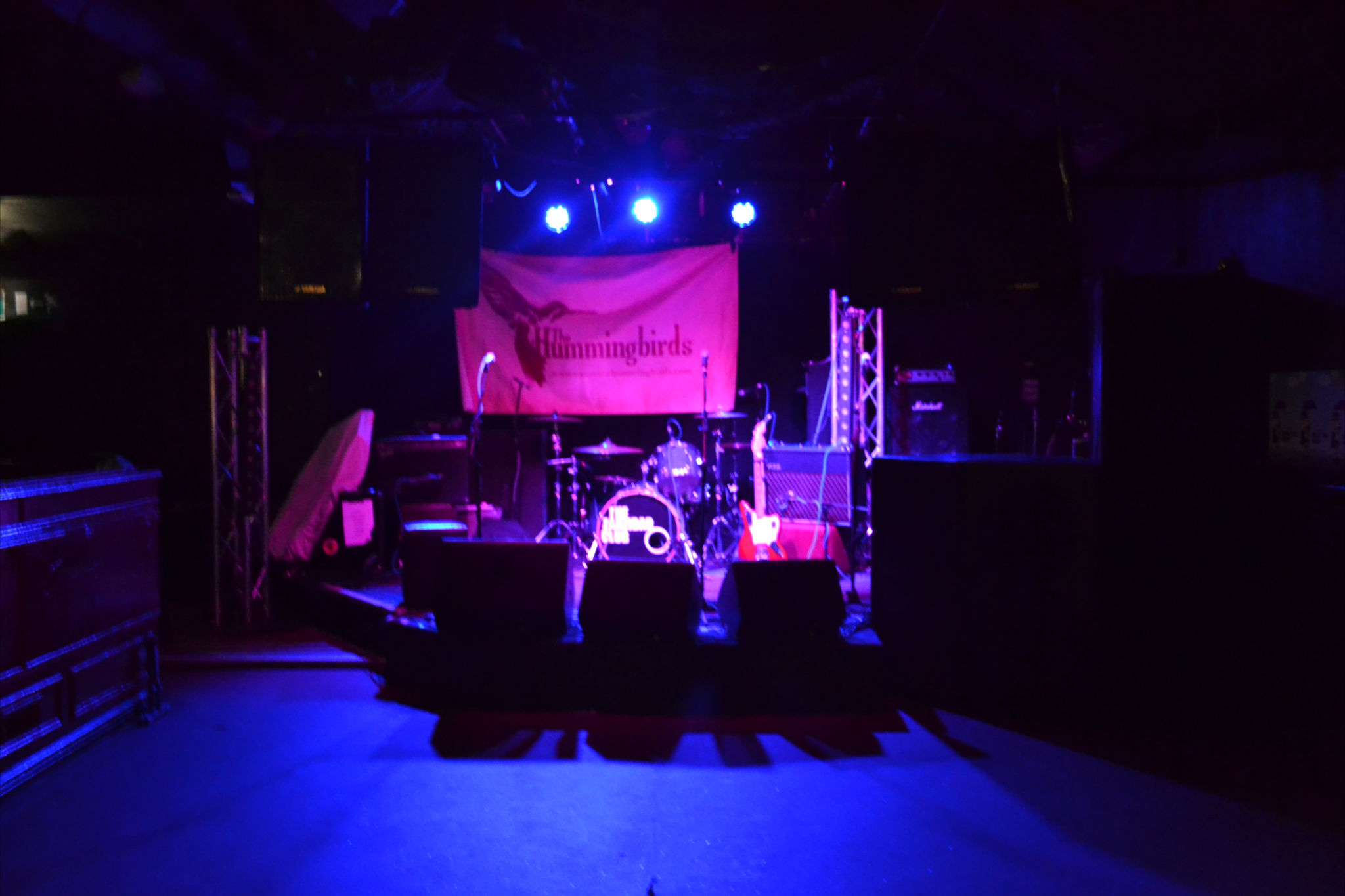 Alt text: Zanzibar Club stage ready for live music event with drum kit and sound equipment.