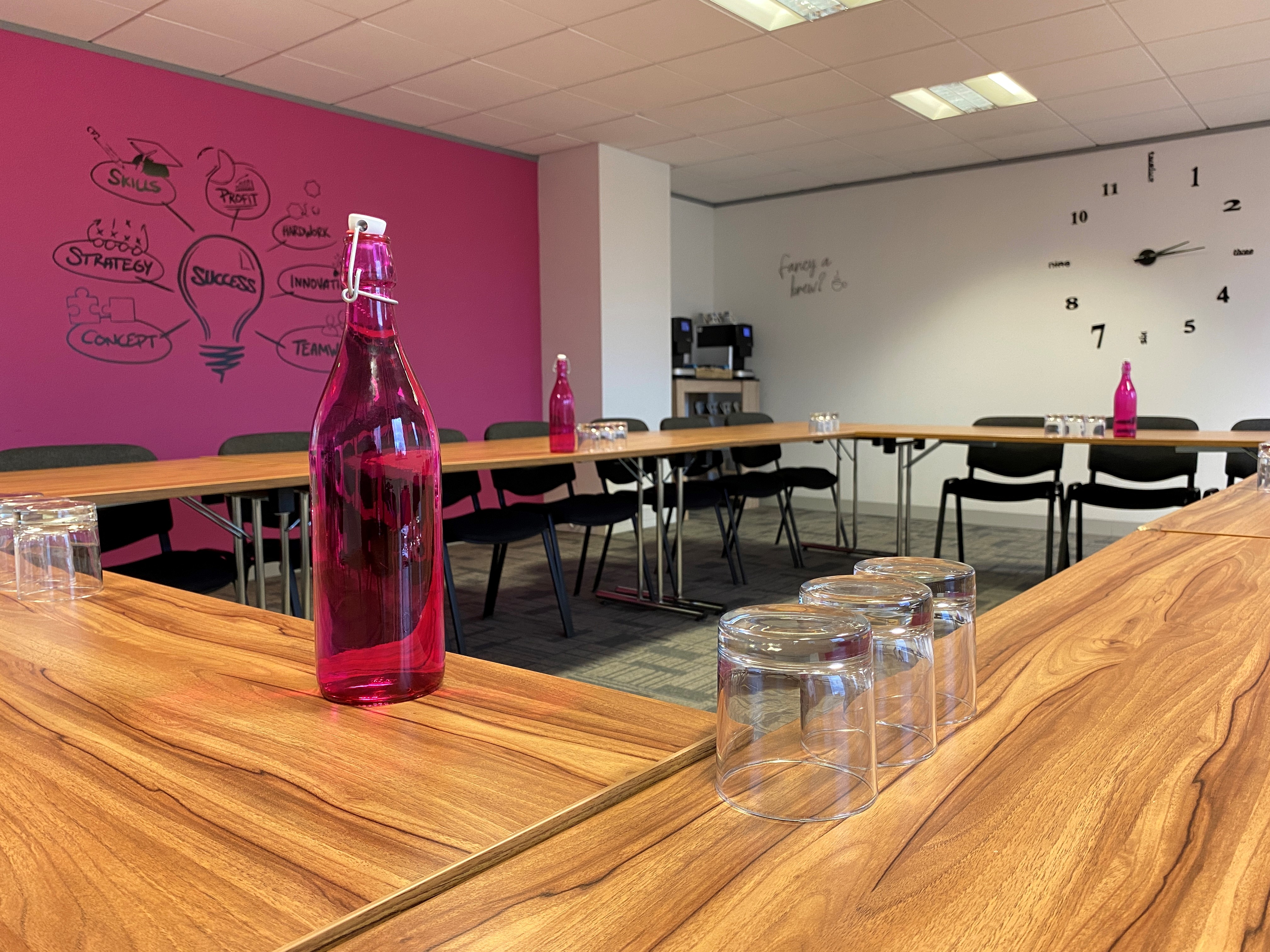 Magenta Suite meeting room at UBC, featuring a vibrant pink wall and circular table setup.