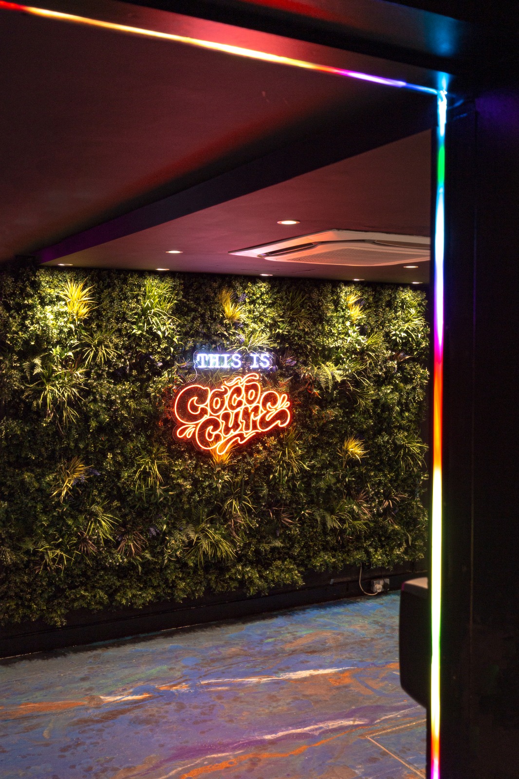 Vibrant Cococure venue with greenery and neon sign for events and workshops.