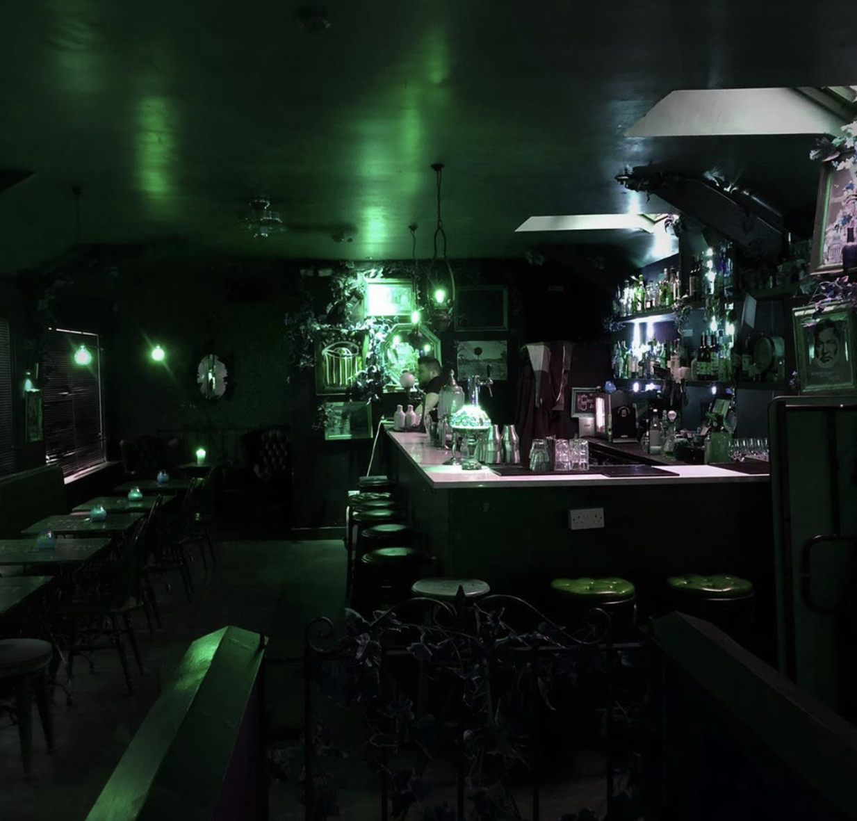 Dimly lit Zanzibar Club bar with glowing green accents for intimate events.