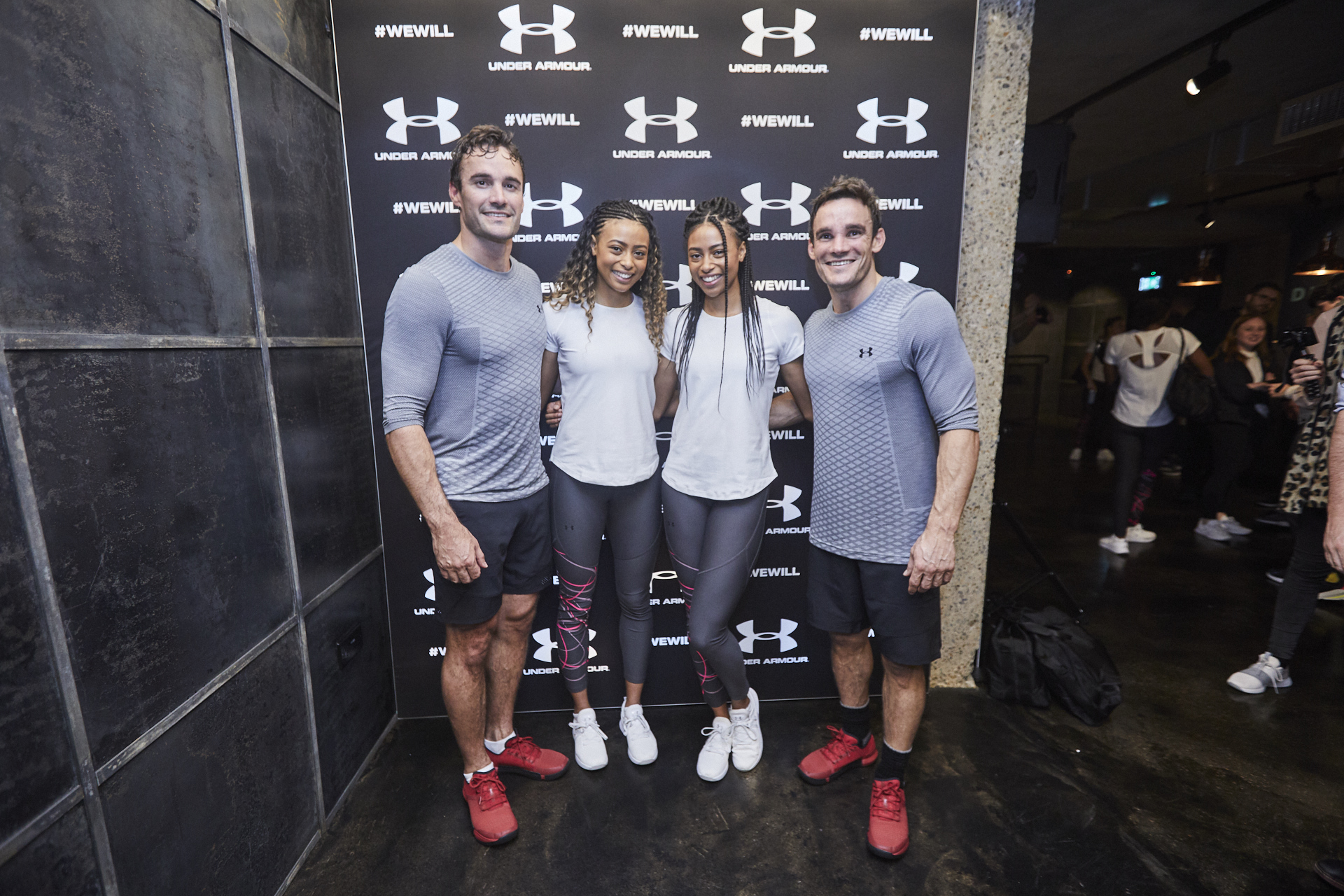 Fitness influencers in athletic wear at Victus Soul event backdrop, promoting health and wellness.