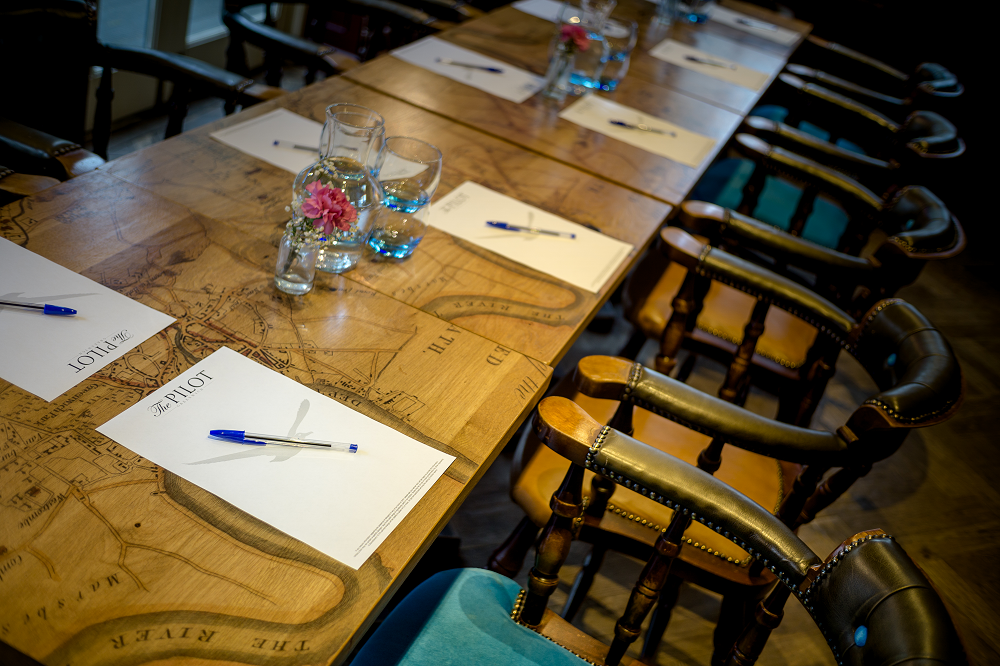 Meeting setup at The Bridge, Pilot Greenwich with elegant floral accents and wooden table.