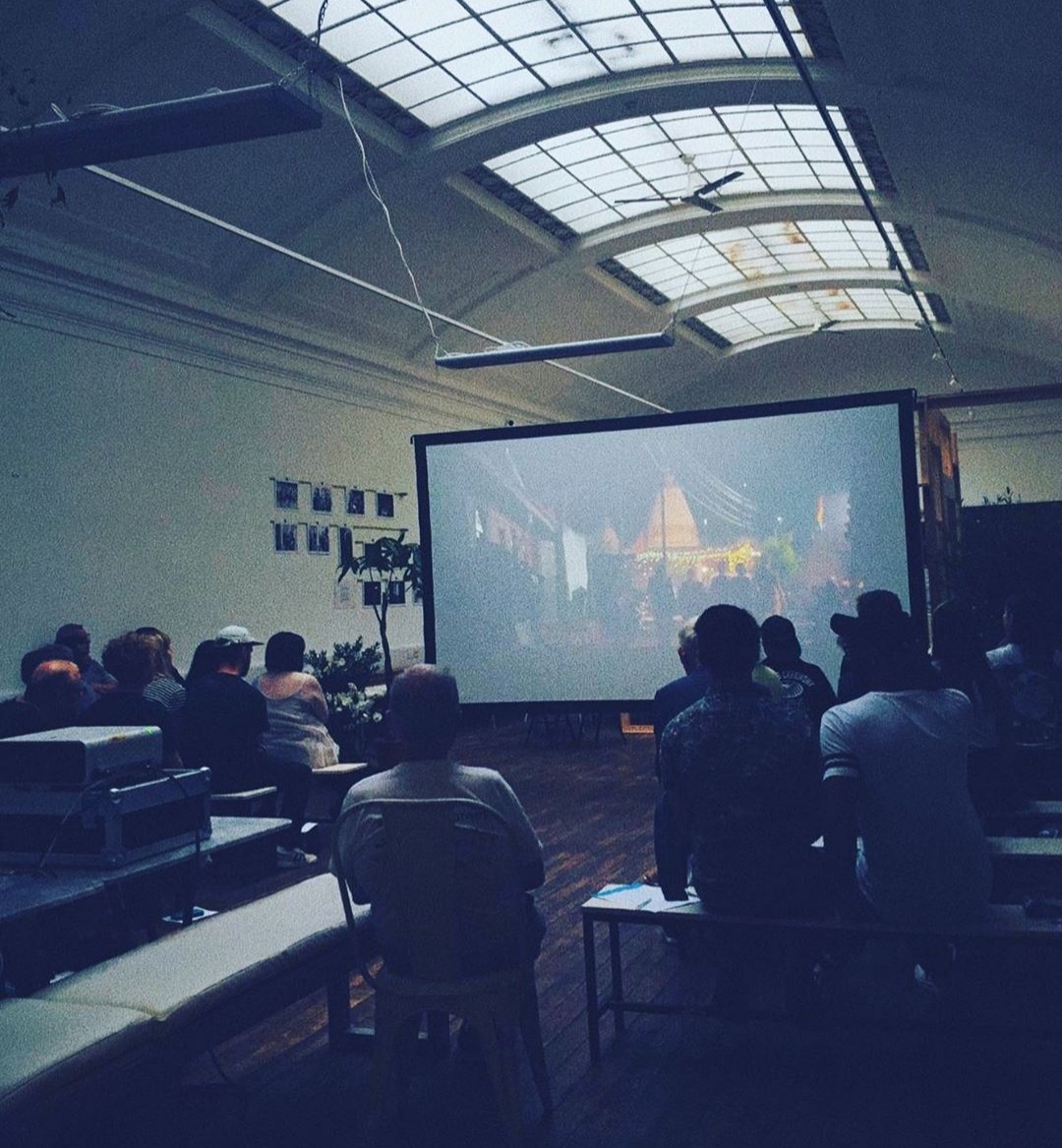 Attendees at a presentation in Medicine Gallery, showcasing a large screen for multimedia events.