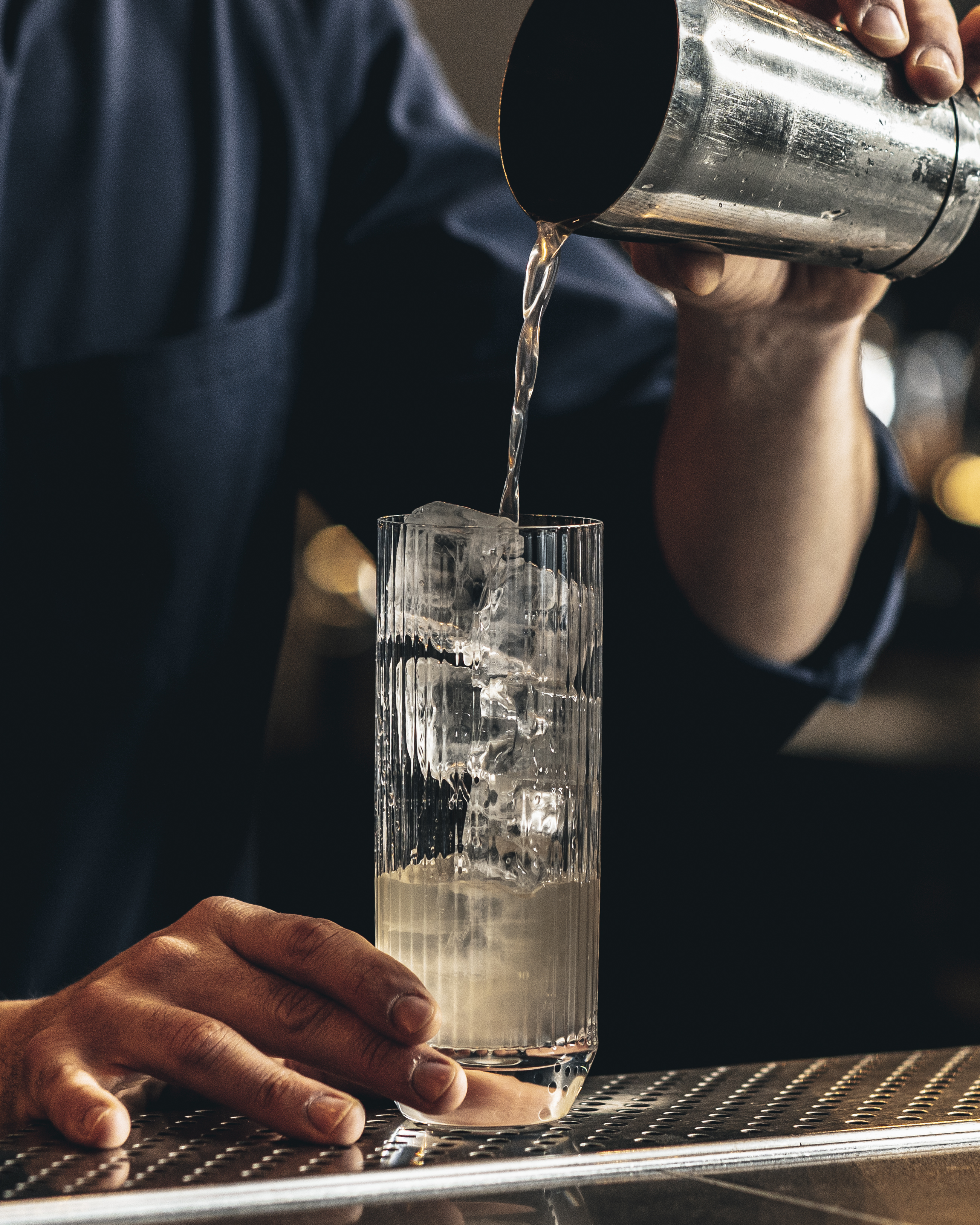 Bartender pouring drink over ice at Chotto Matte Bar and Lounge, perfect for events.