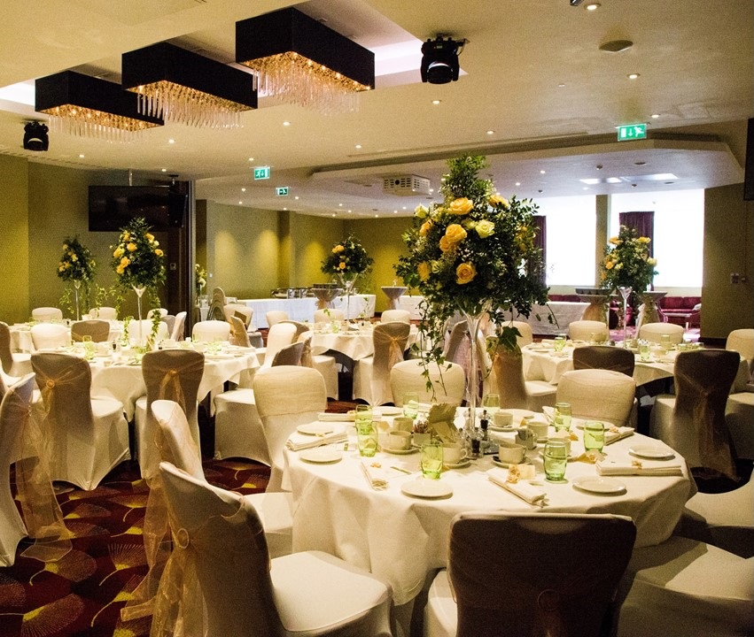 Elegant wedding banquet at Holiday Inn Kensington, featuring white linens and yellow flowers.