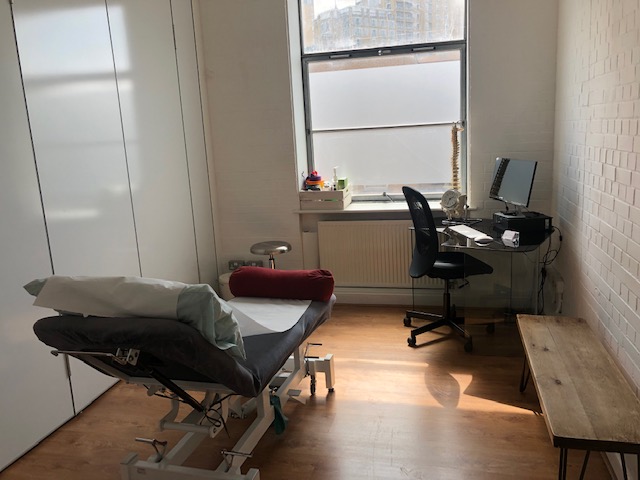 Well-lit consultation room with medical table, ideal for wellness retreats and workshops.