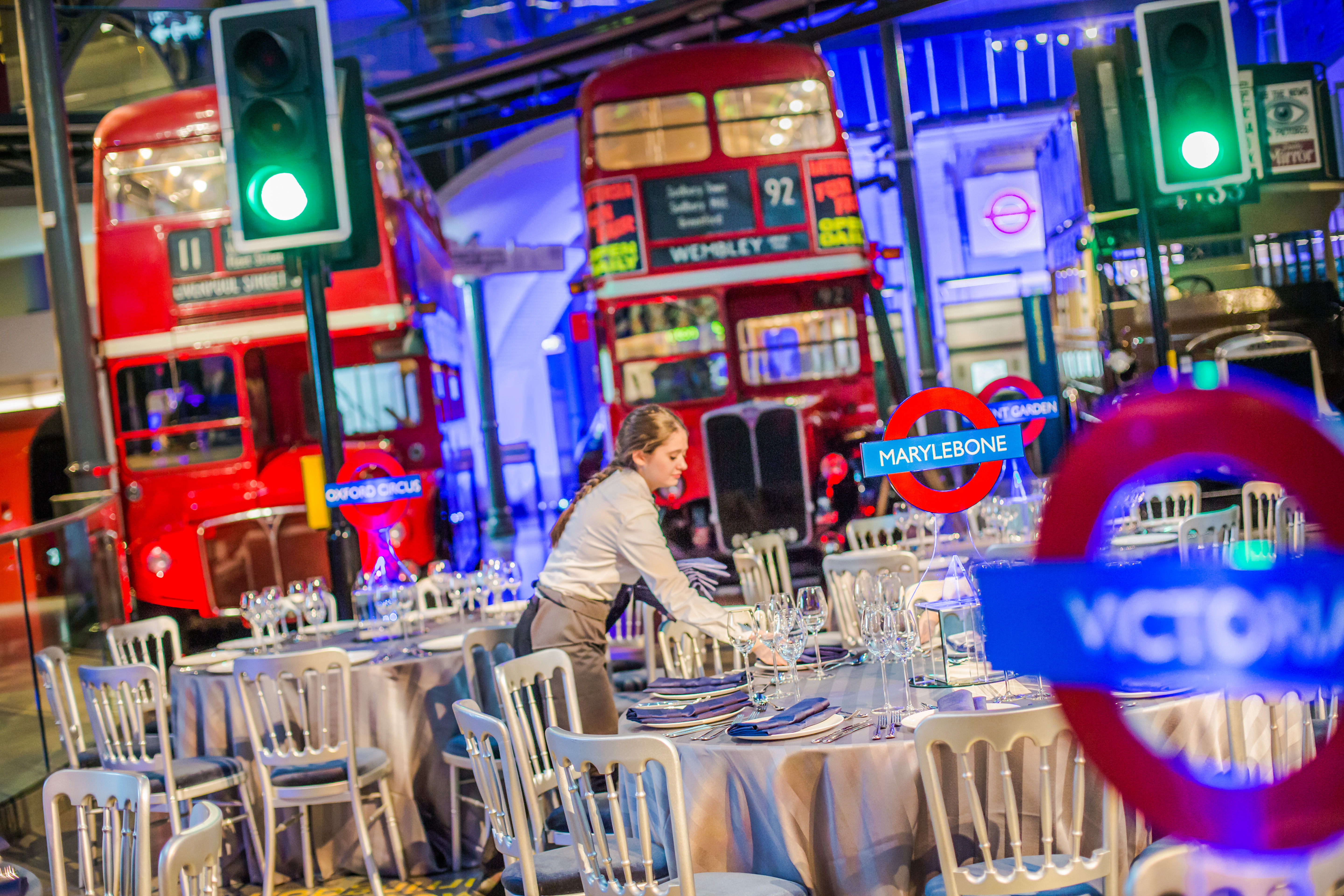 Elegant event space in London Transport Museum with red double-decker buses and themed decor.