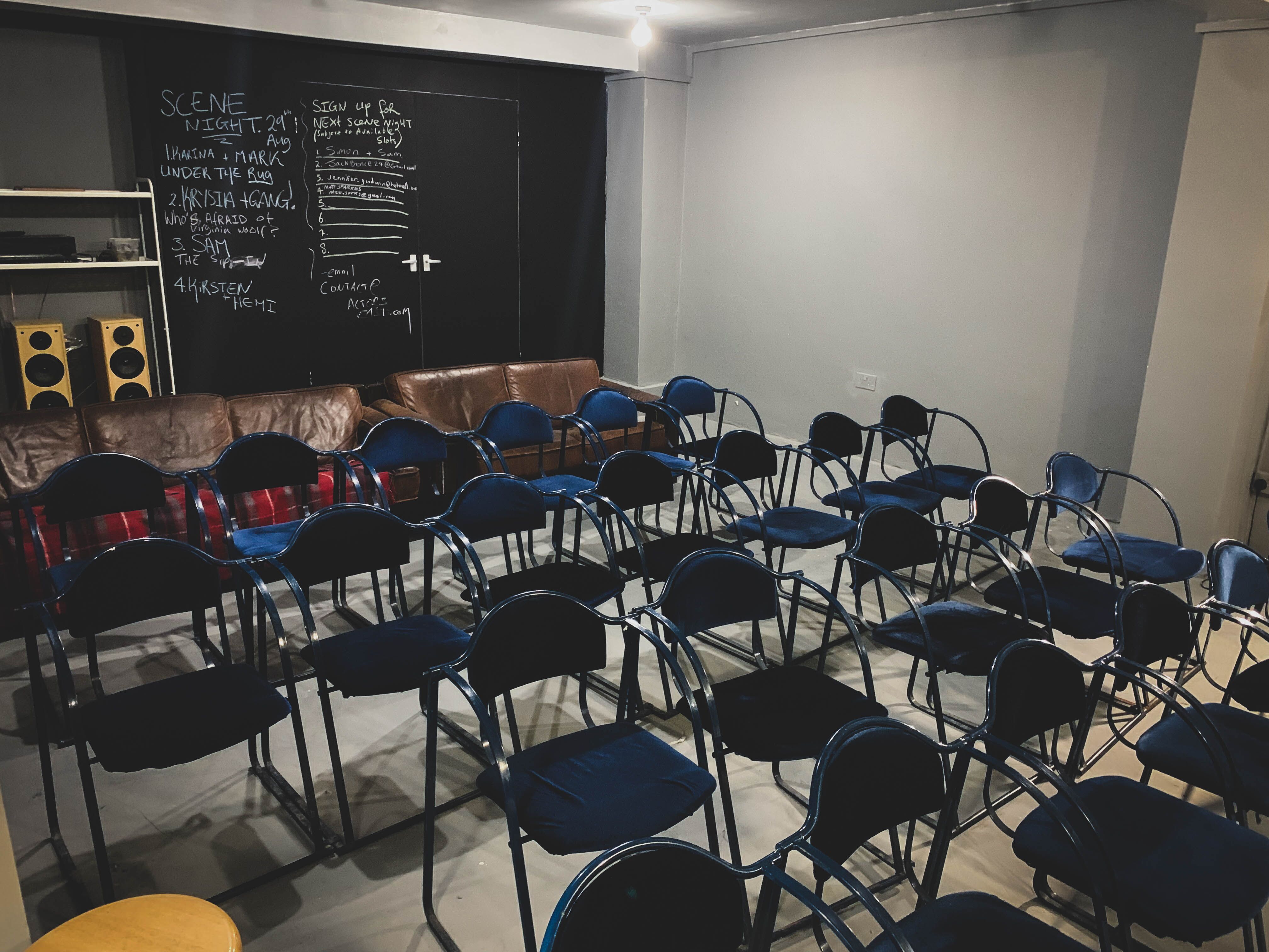 Minimalist event space in AE Studio with blue chairs for meetings and workshops.