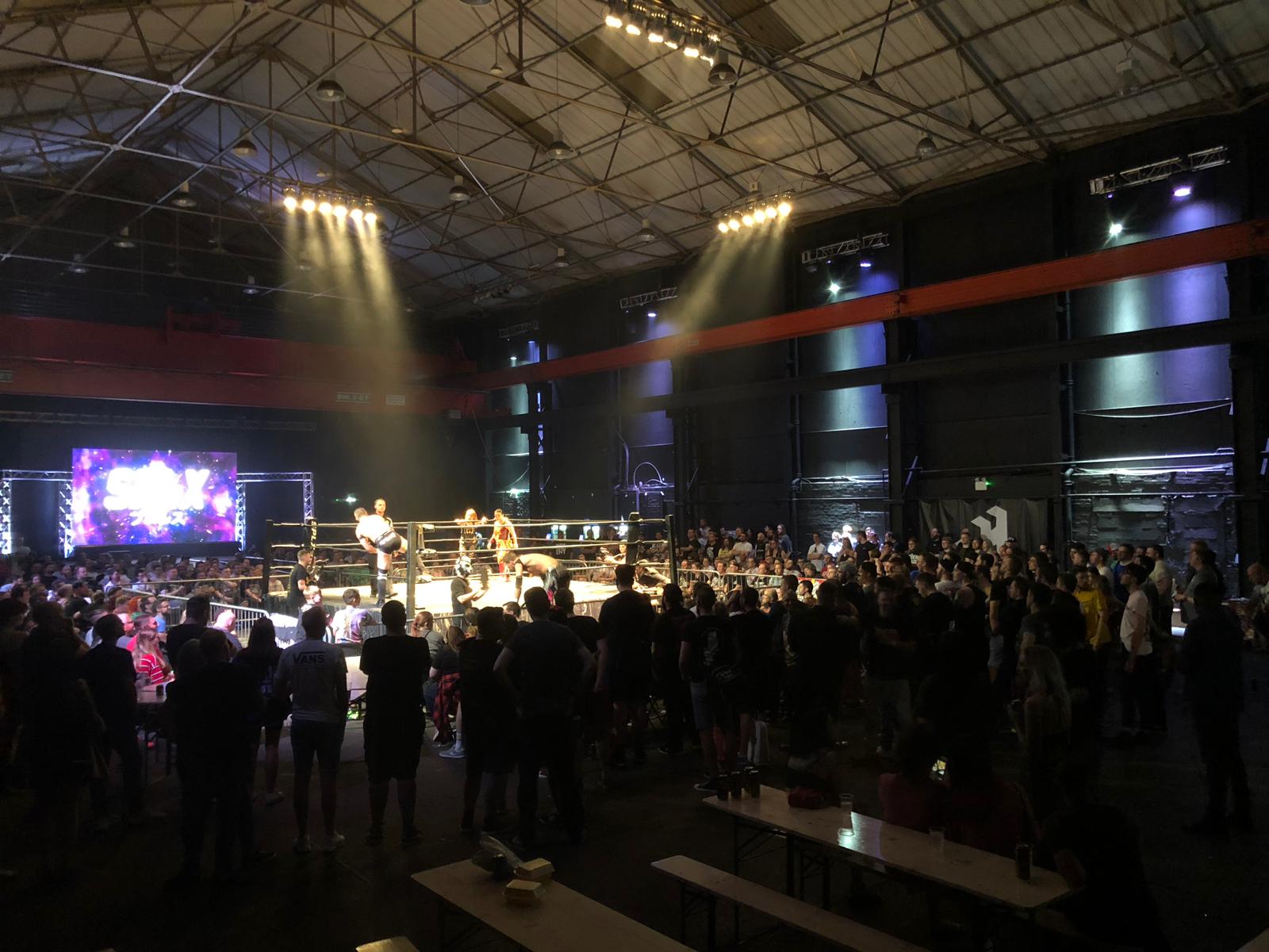 Wrestling match setup in dynamic event space with engaged audience and vibrant lighting.