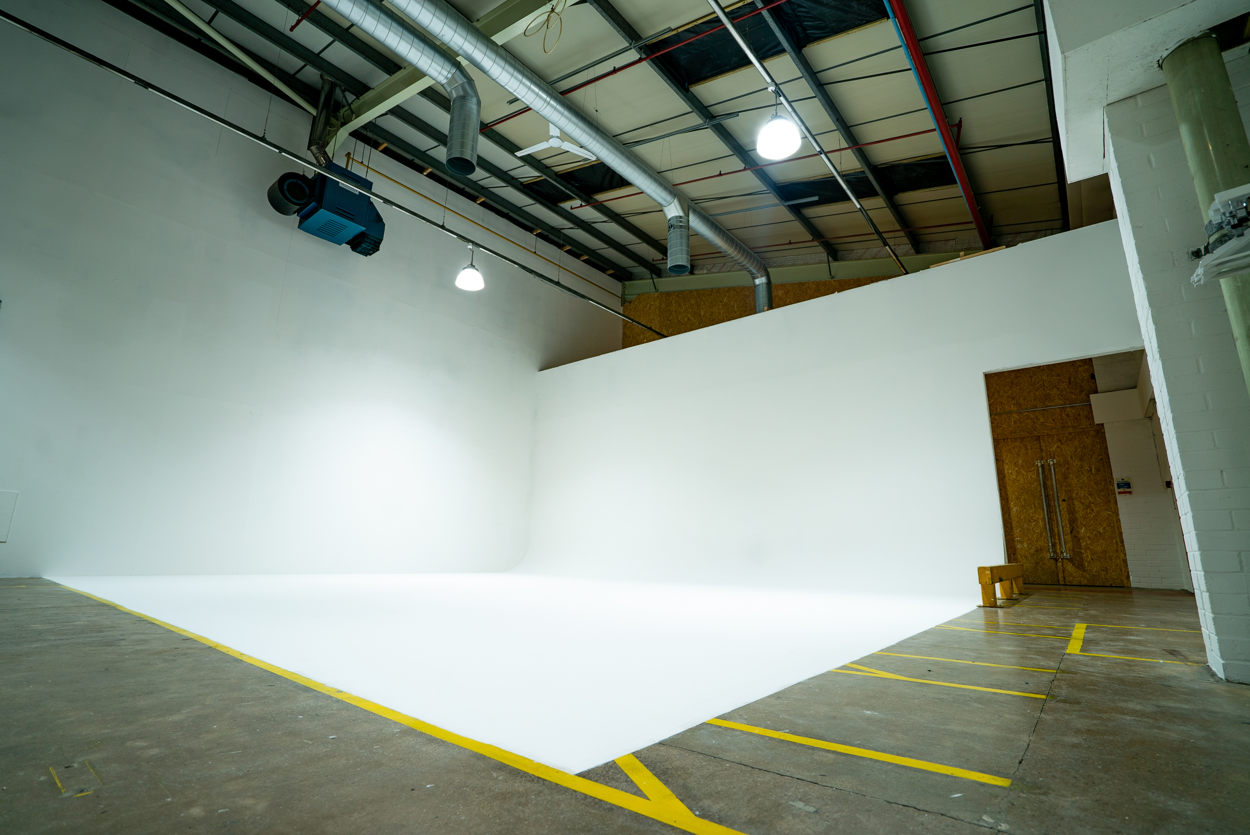 Versatile event space with white backdrop, ideal for meetings and workshops.