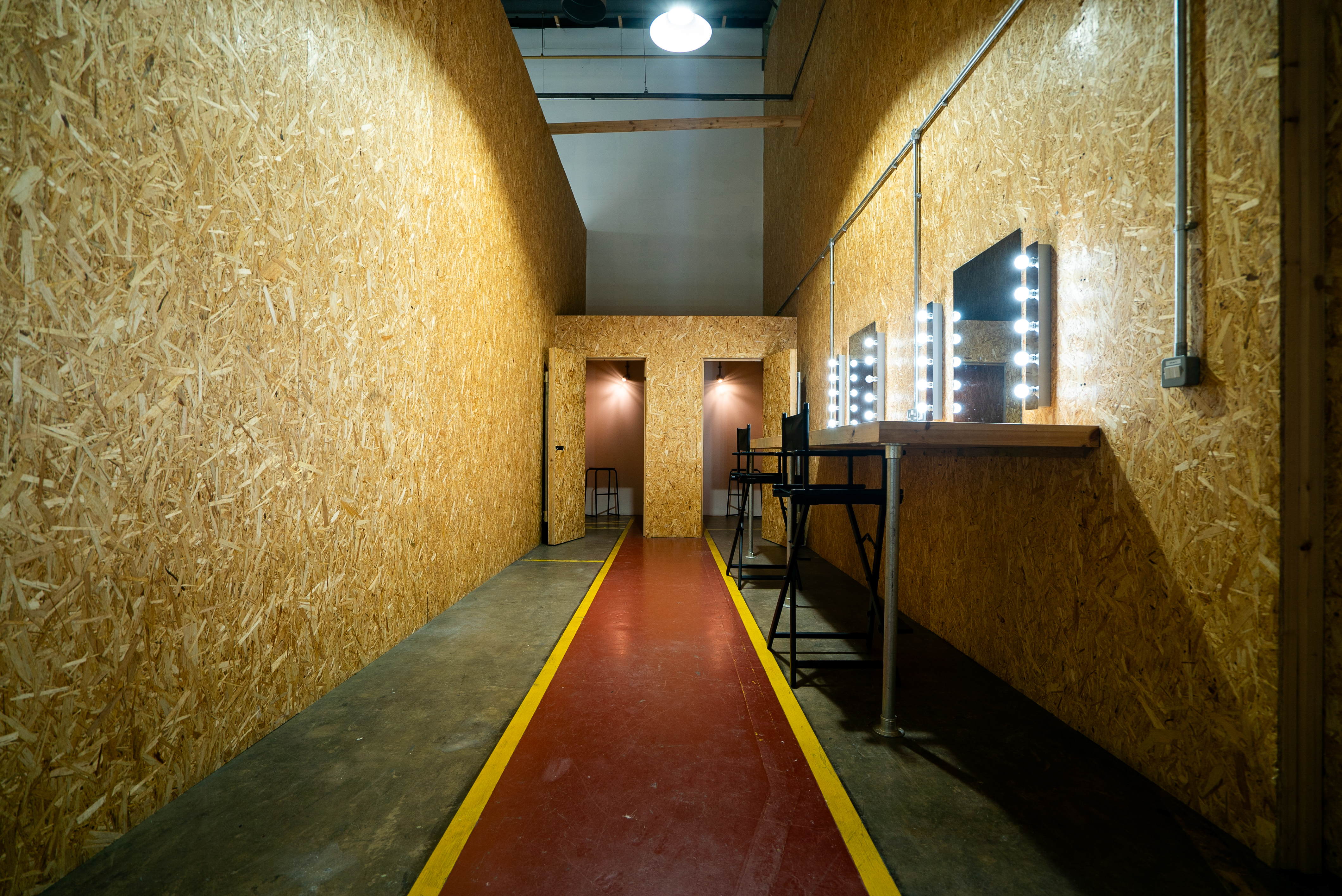 Backstage corridor with wooden walls and red carpet at [Un.titled] Studio event.