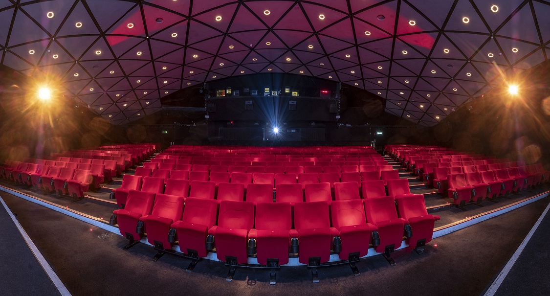 Modern auditorium with red seating, ideal for conferences and film screenings.