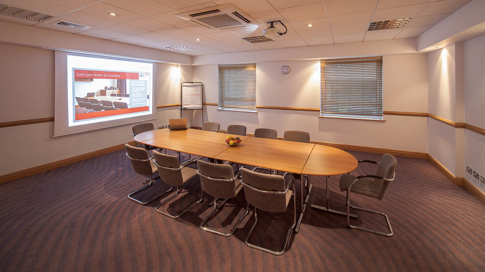 Meeting room with oval table and projector screen for workshops in Jury's Inn Glasgow.