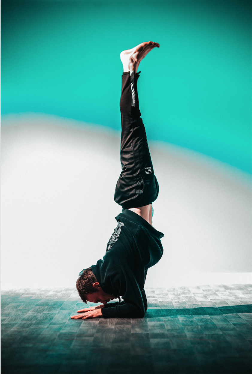 Dynamic performer in handstand at Graystone Action Sports Academy yoga studio event.