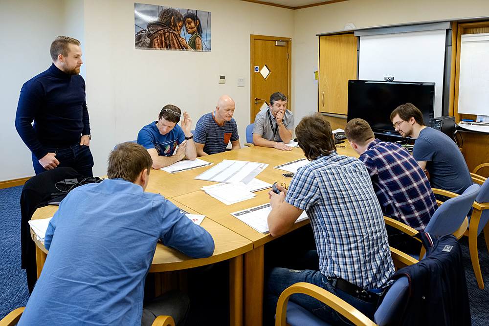 Conference room meeting with engaged participants, documents for strategic planning.