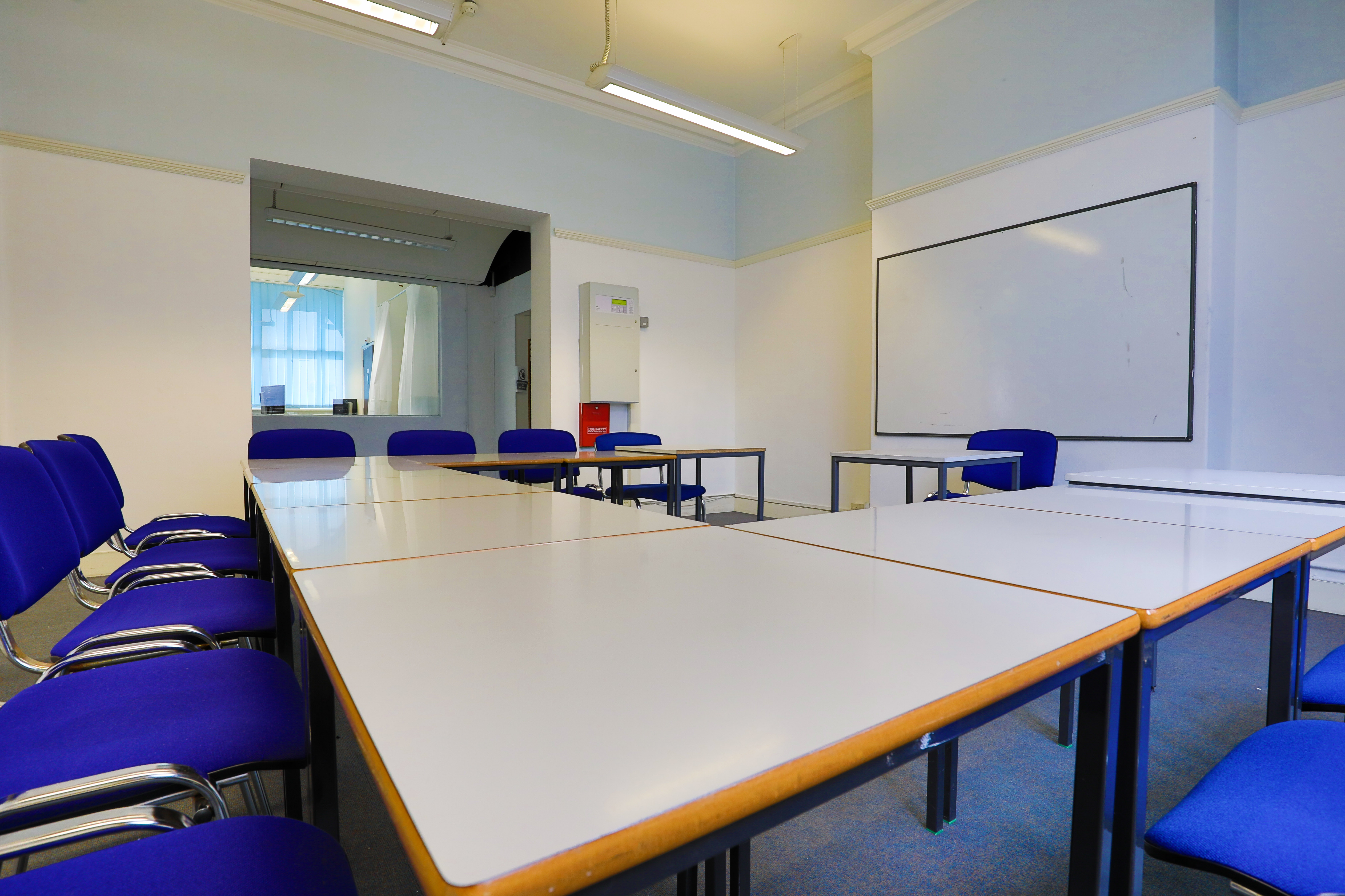 Conference room with large table and blue chairs, ideal for meetings and brainstorming sessions.