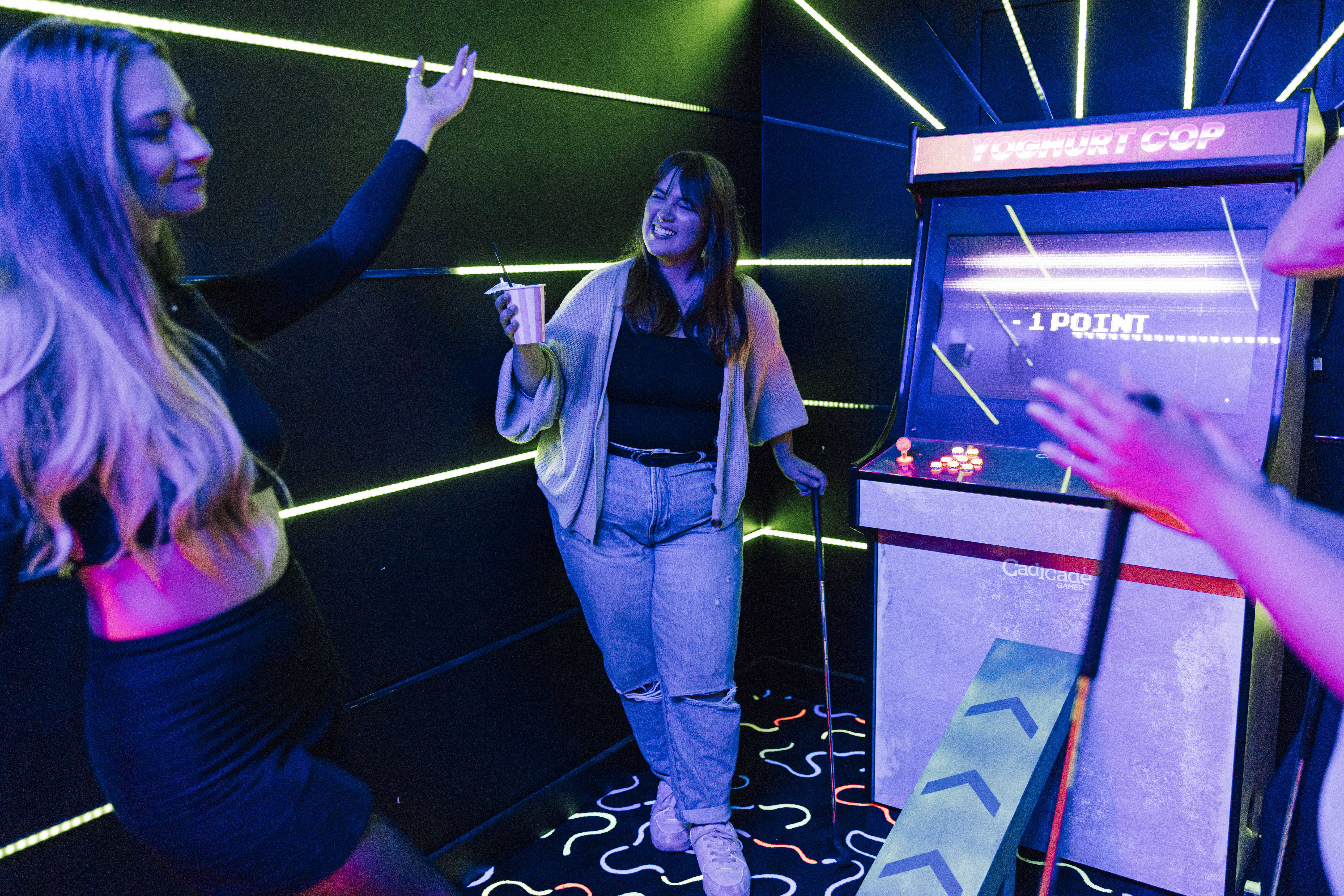 Vibrant event space with neon lights and arcade games for team-building activities.