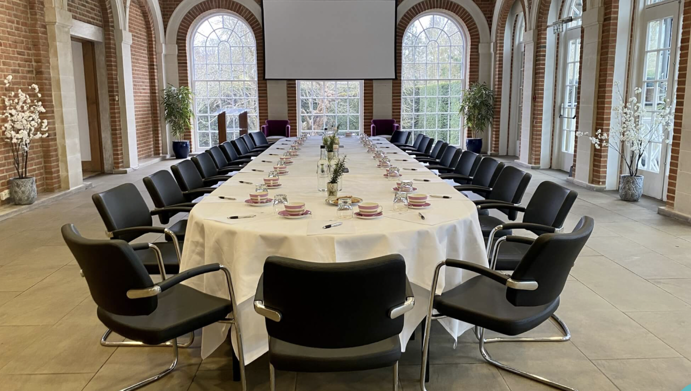 Orangery meeting space with oval table, perfect for formal events and gatherings.