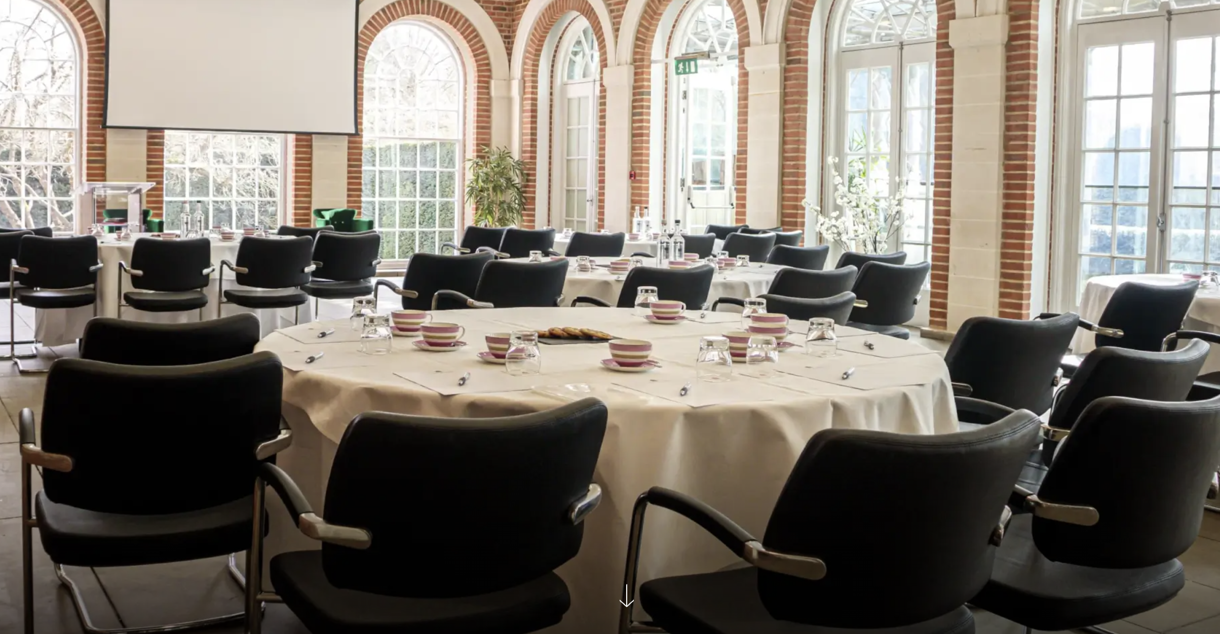 Orangery meeting space with round table, ideal for workshops and discussions.