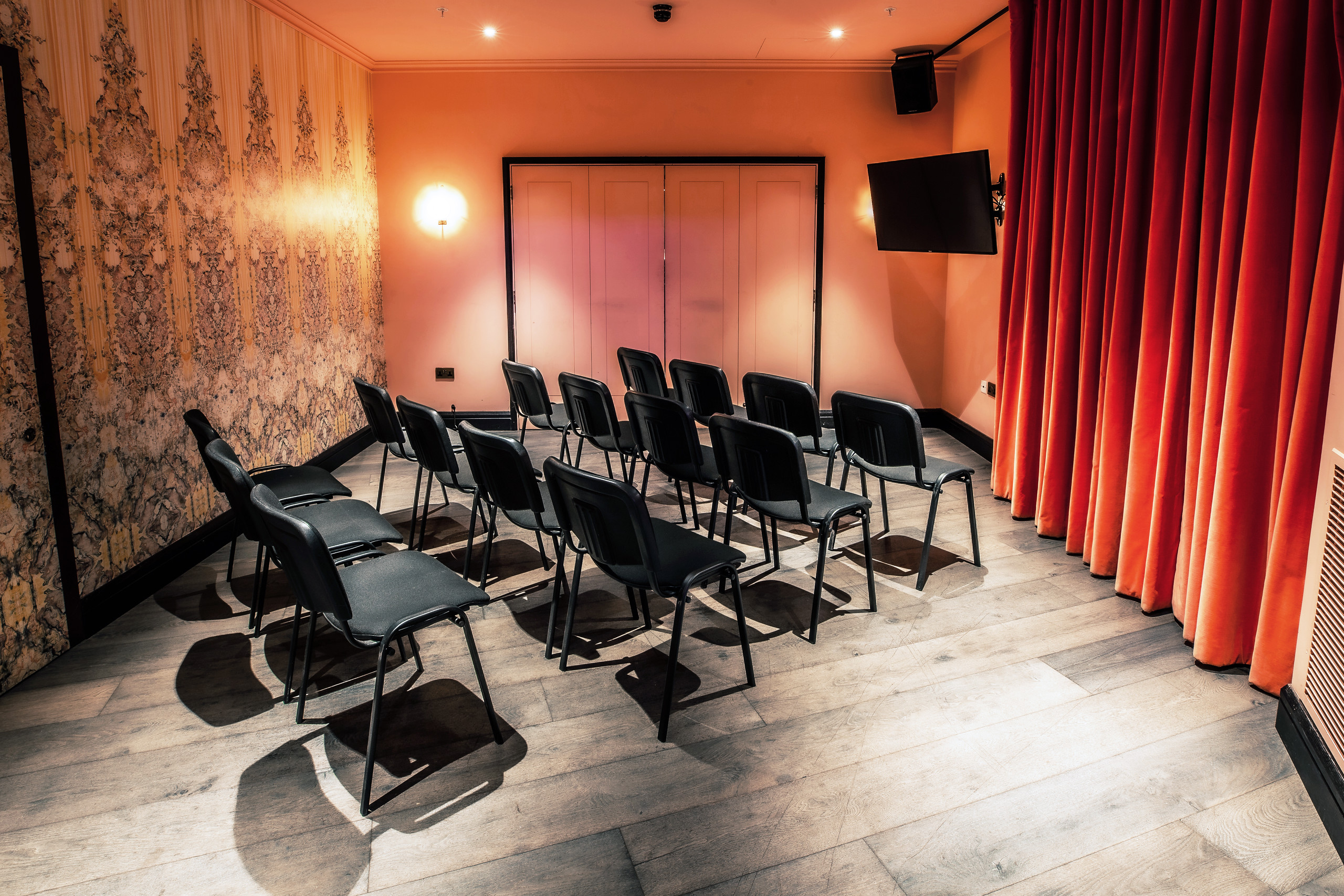 Intimate meeting room with black chairs and screen for presentations at Puttshack Bank.