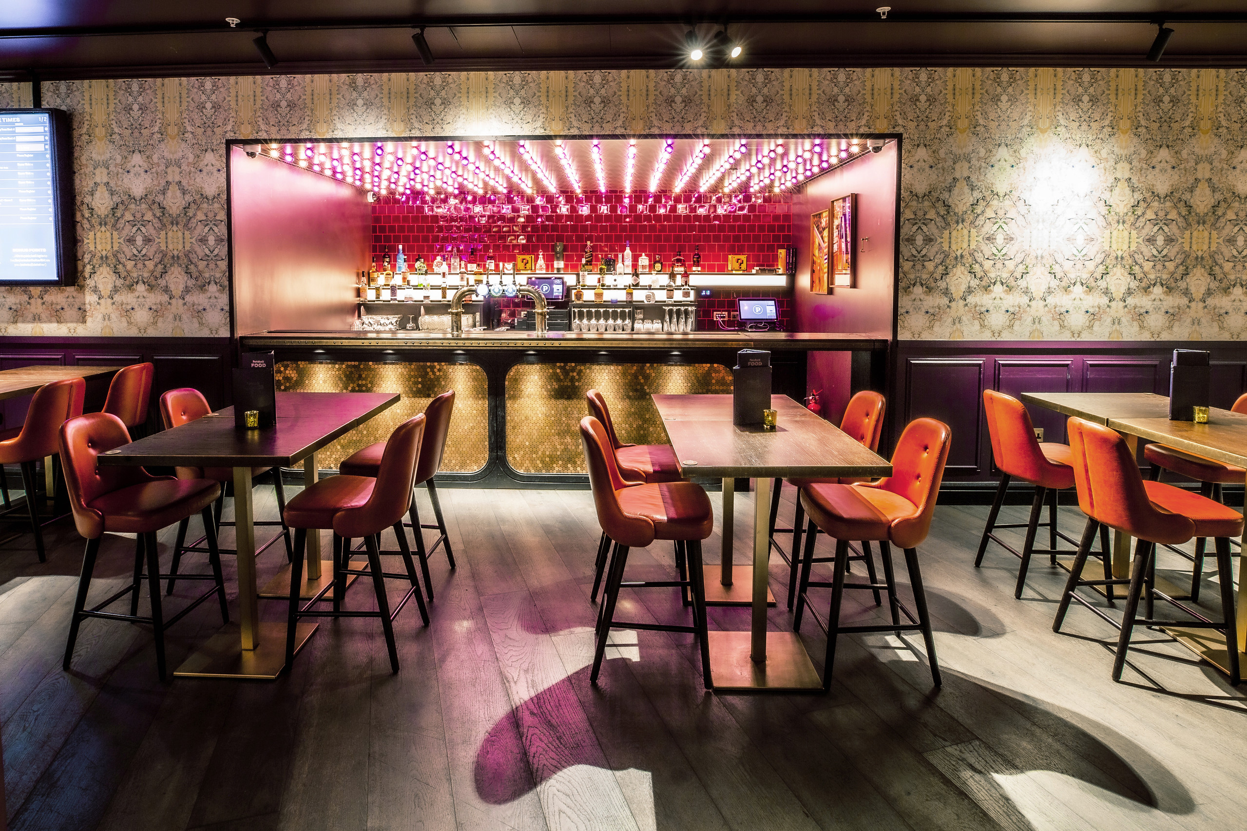 Ruby Private Room at Puttshack Bank: modern bar, vibrant seating for events and gatherings.