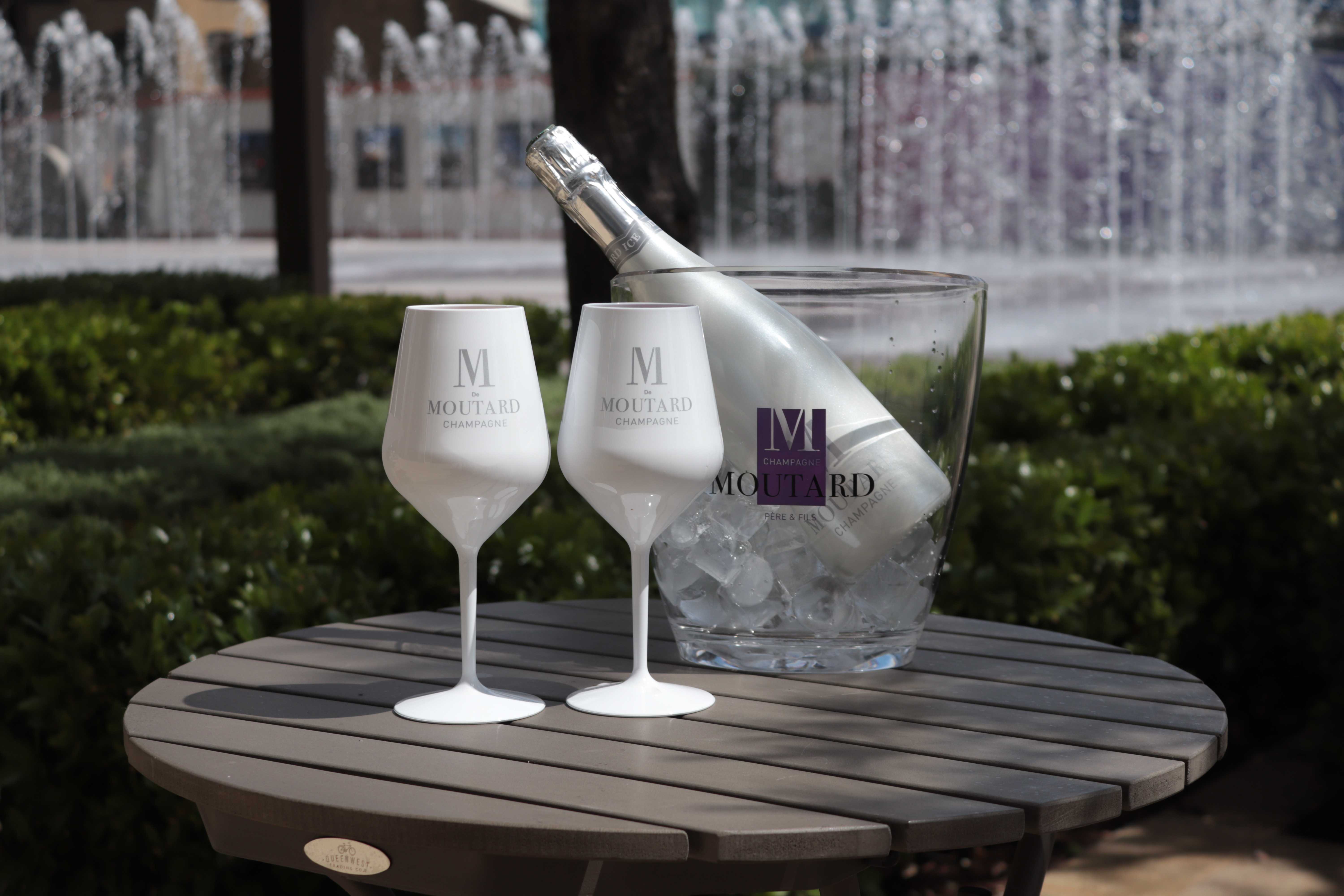 Elegant outdoor event setup with champagne, glasses, and fountain ambiance.