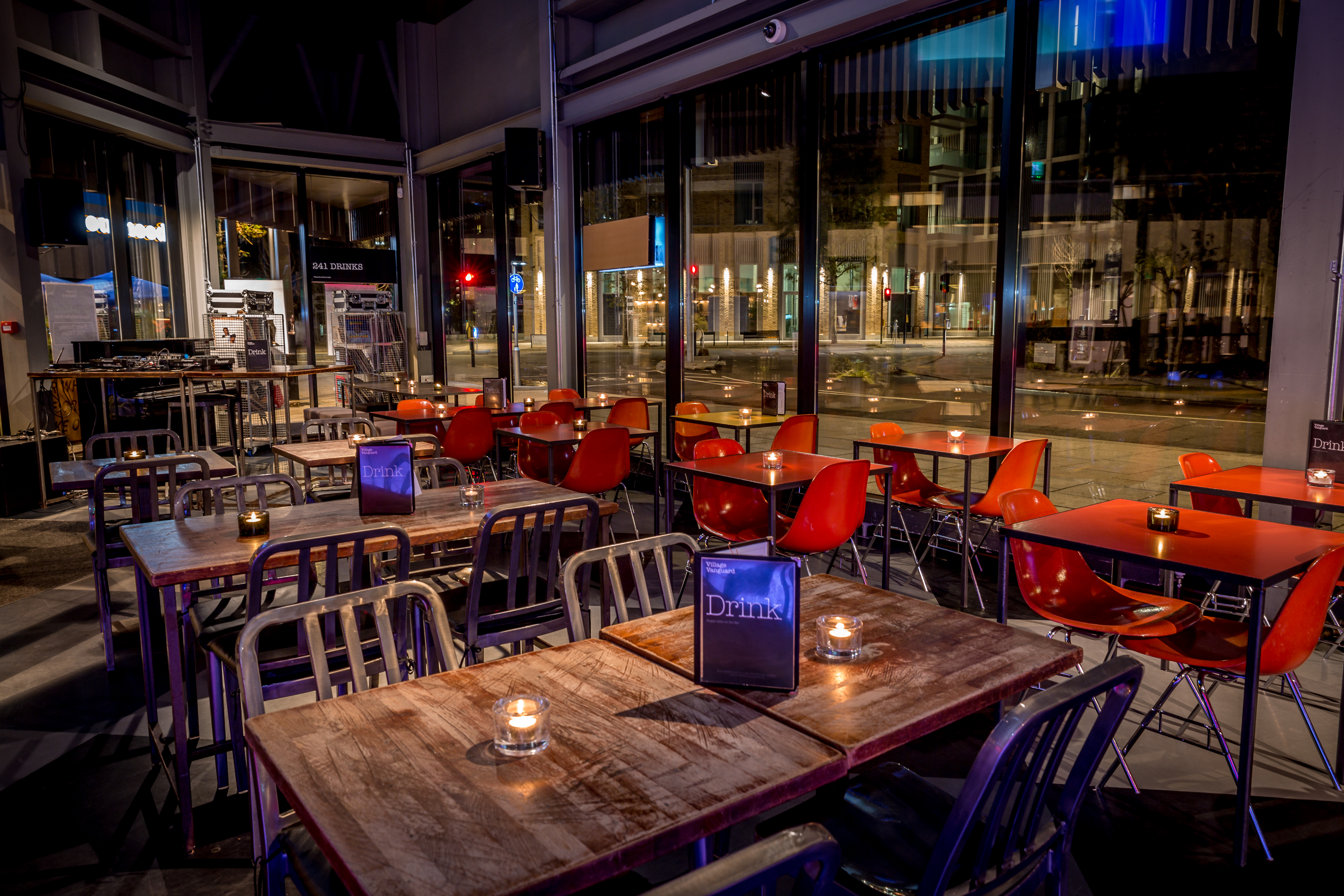 Modern event space with wooden tables and red chairs, perfect for networking or gatherings.