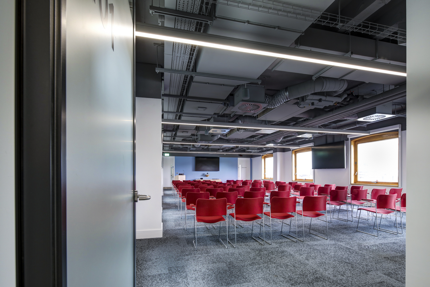 Modern meeting room with red chairs, ideal for conferences and workshops.