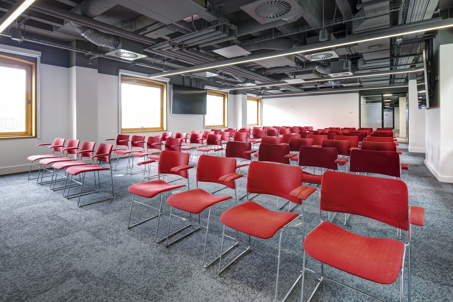 Modern meeting space with red chairs, ideal for presentations and workshops.