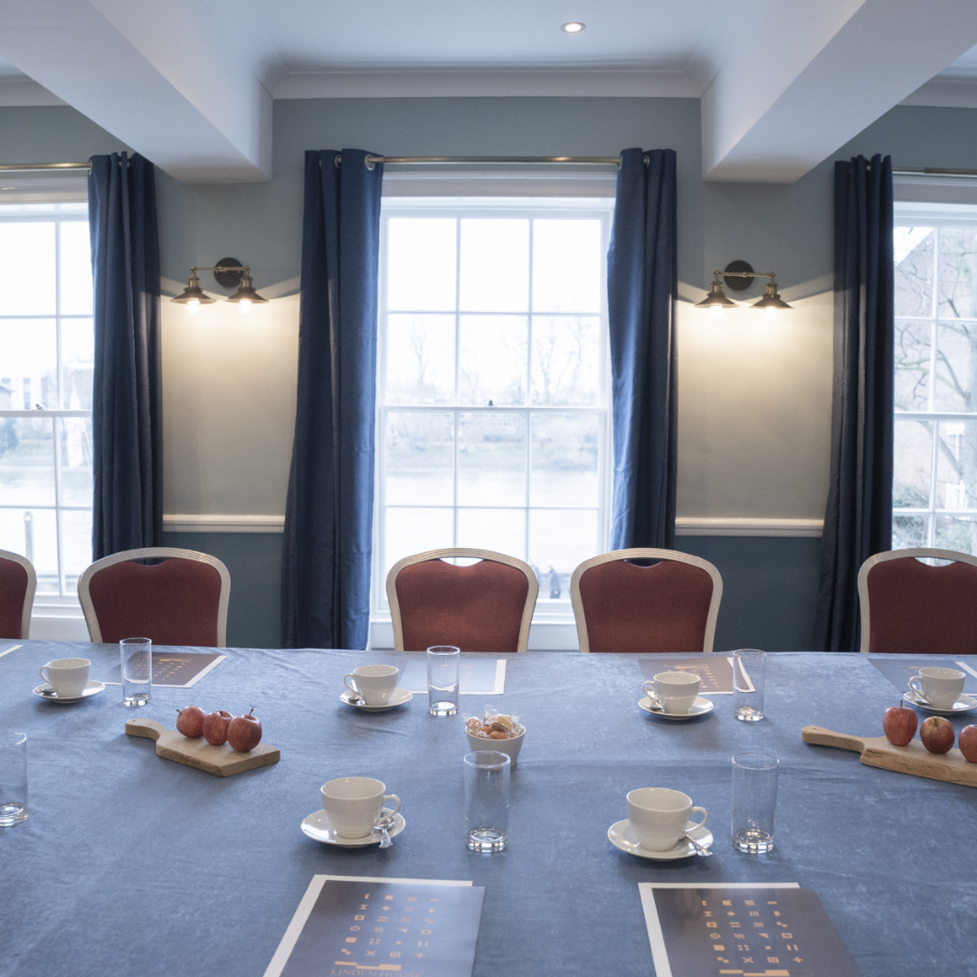 Elegant meeting room with long table, natural light, ideal for events and discussions.
