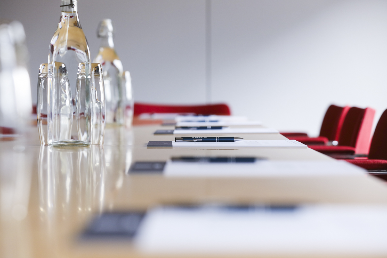 Meeting space with long table, water bottles, and red chairs for professional discussions.