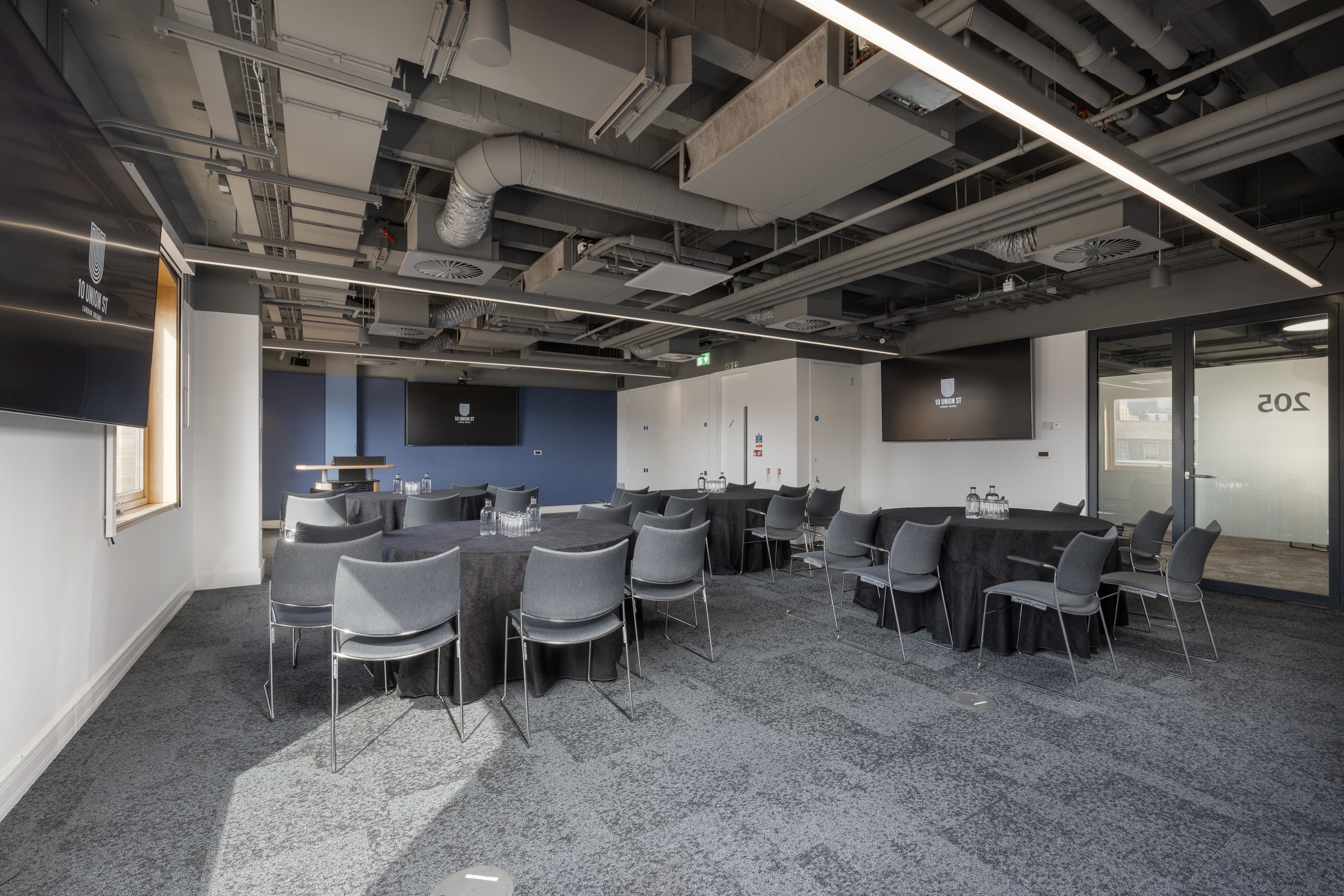 Industrial-chic breakout space with round tables for collaborative workshops and training events.
