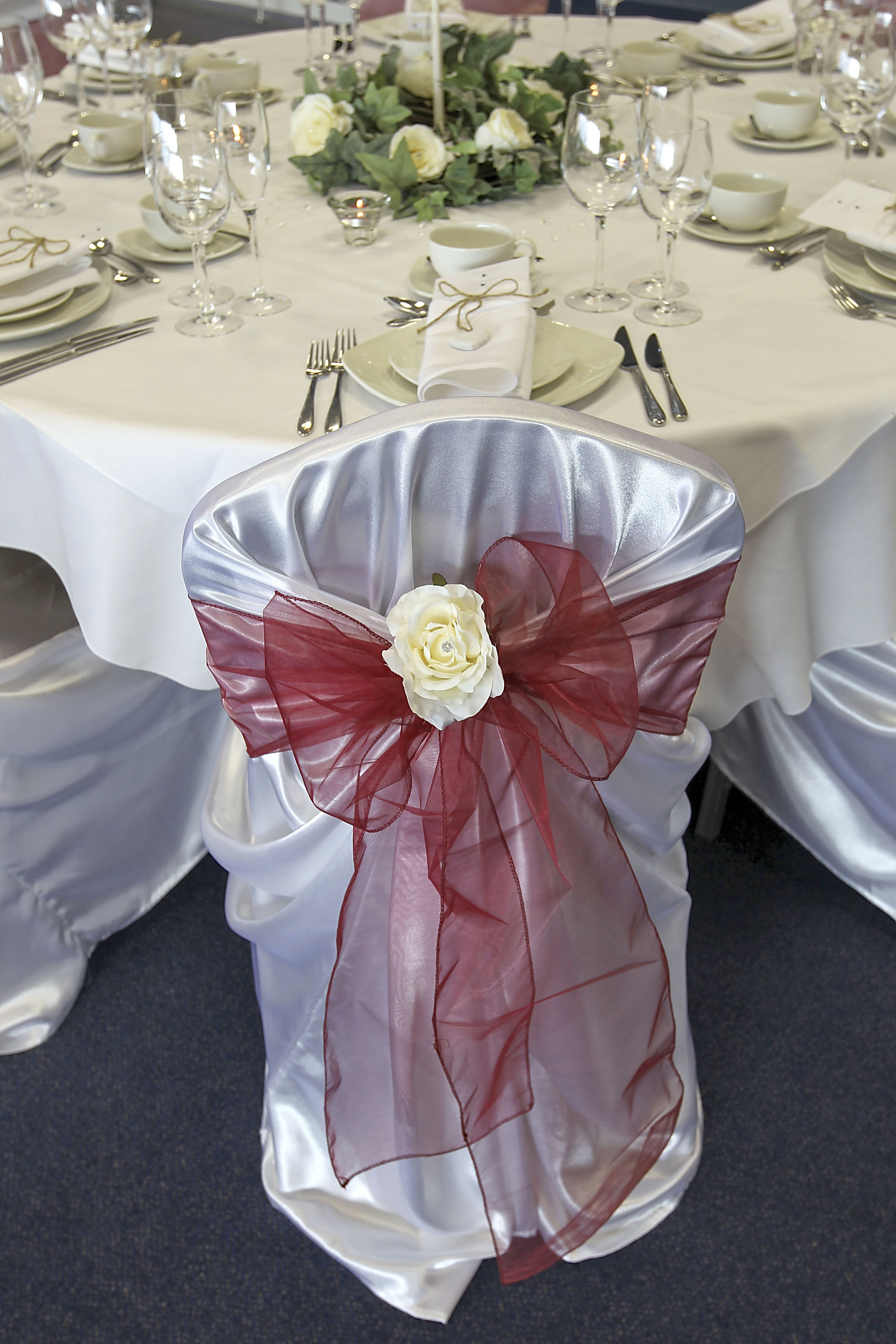 Elegant chair cover with satin bow and rose at Sixways Stadium for weddings and events.