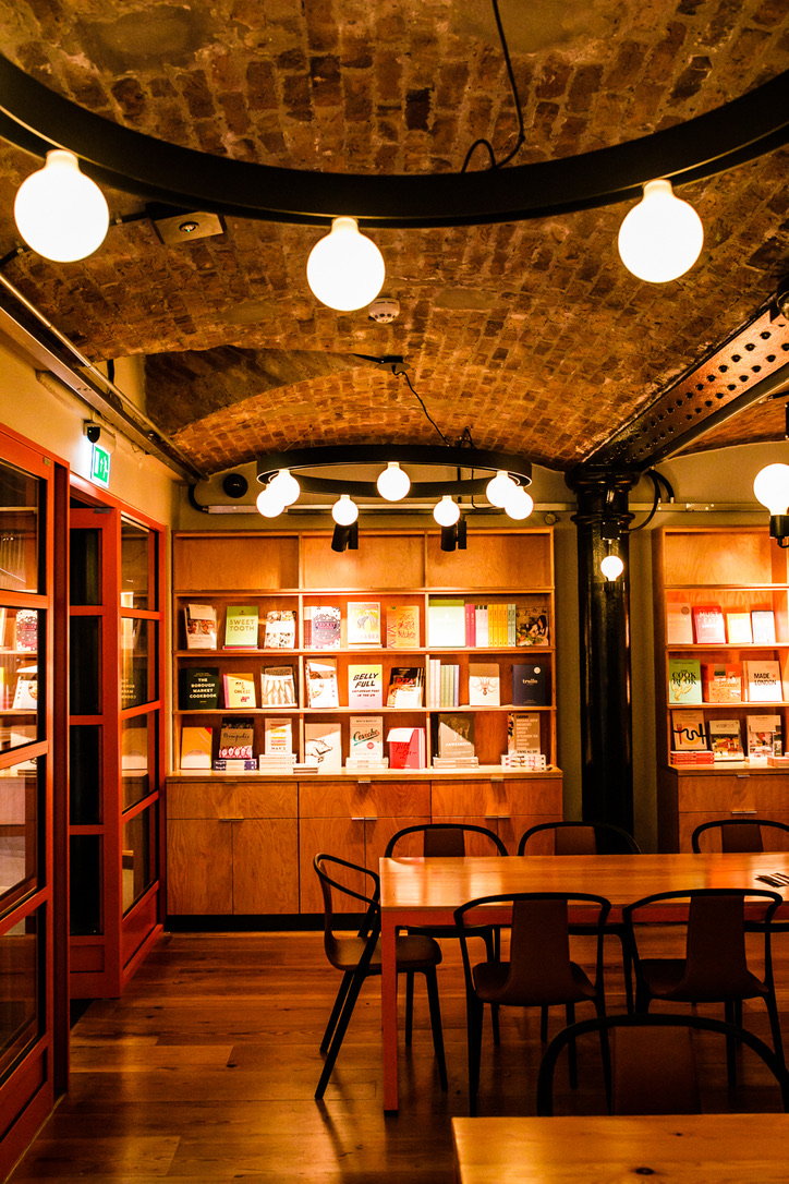 Cozy bookshop meeting space with wooden shelves, perfect for workshops and discussions.