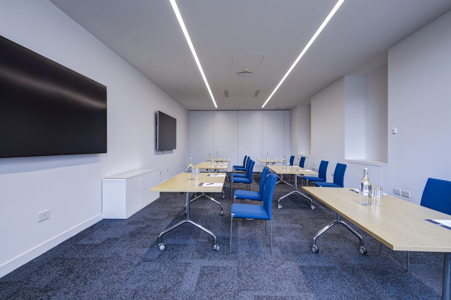 Modern meeting room 303 at 10 Union St. with blue chairs, ideal for workshops and corporate meetings.