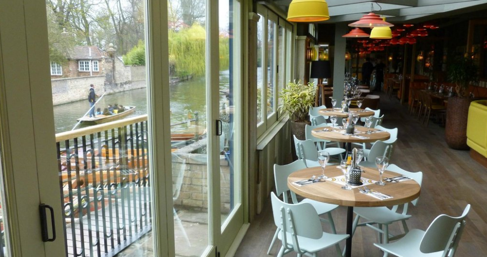 Stylish riverside venue with wooden tables, perfect for events in Cambridge.