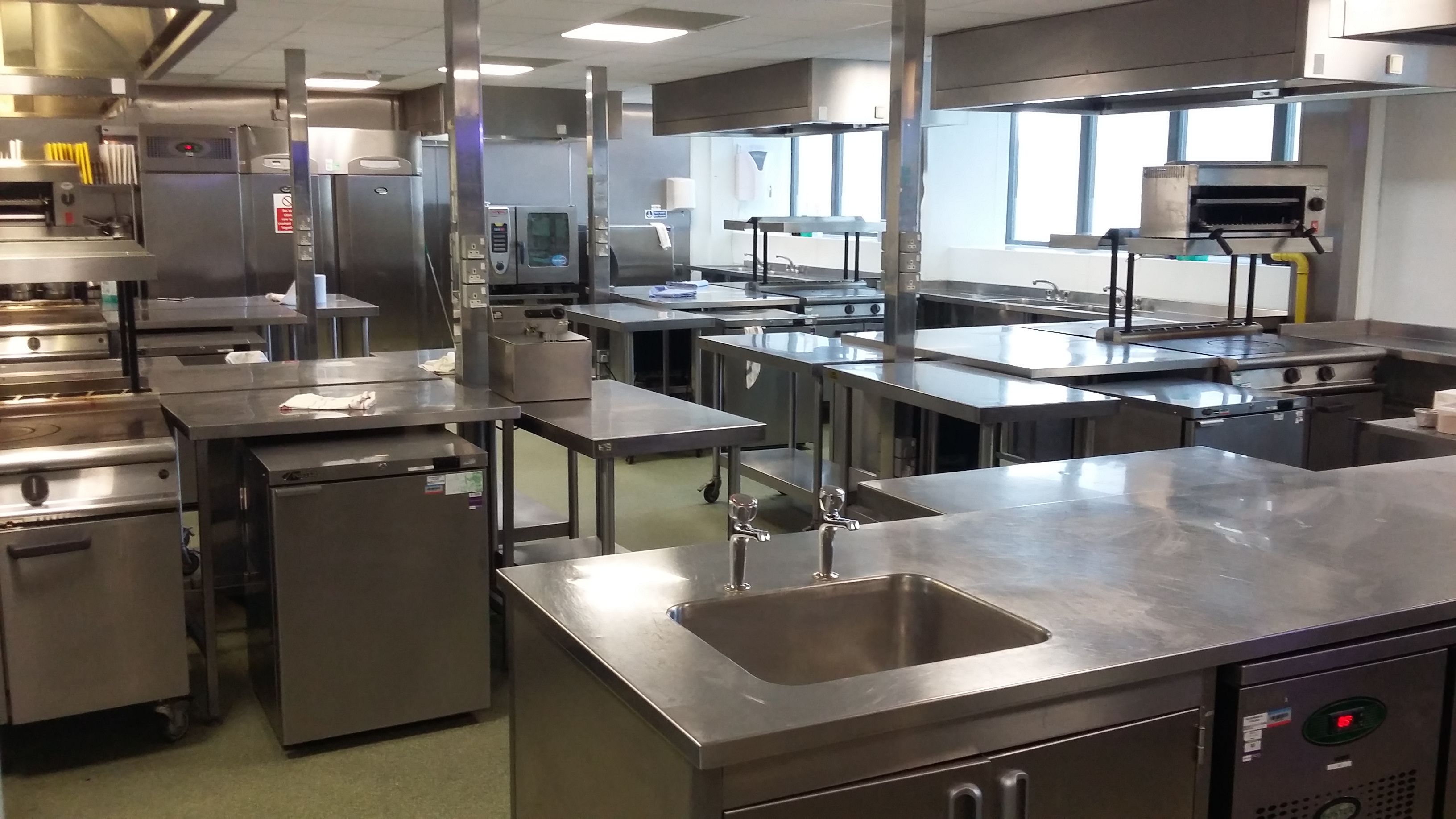Pillars Kitchen at UWL: spacious commercial kitchen with stainless steel surfaces for catering events.