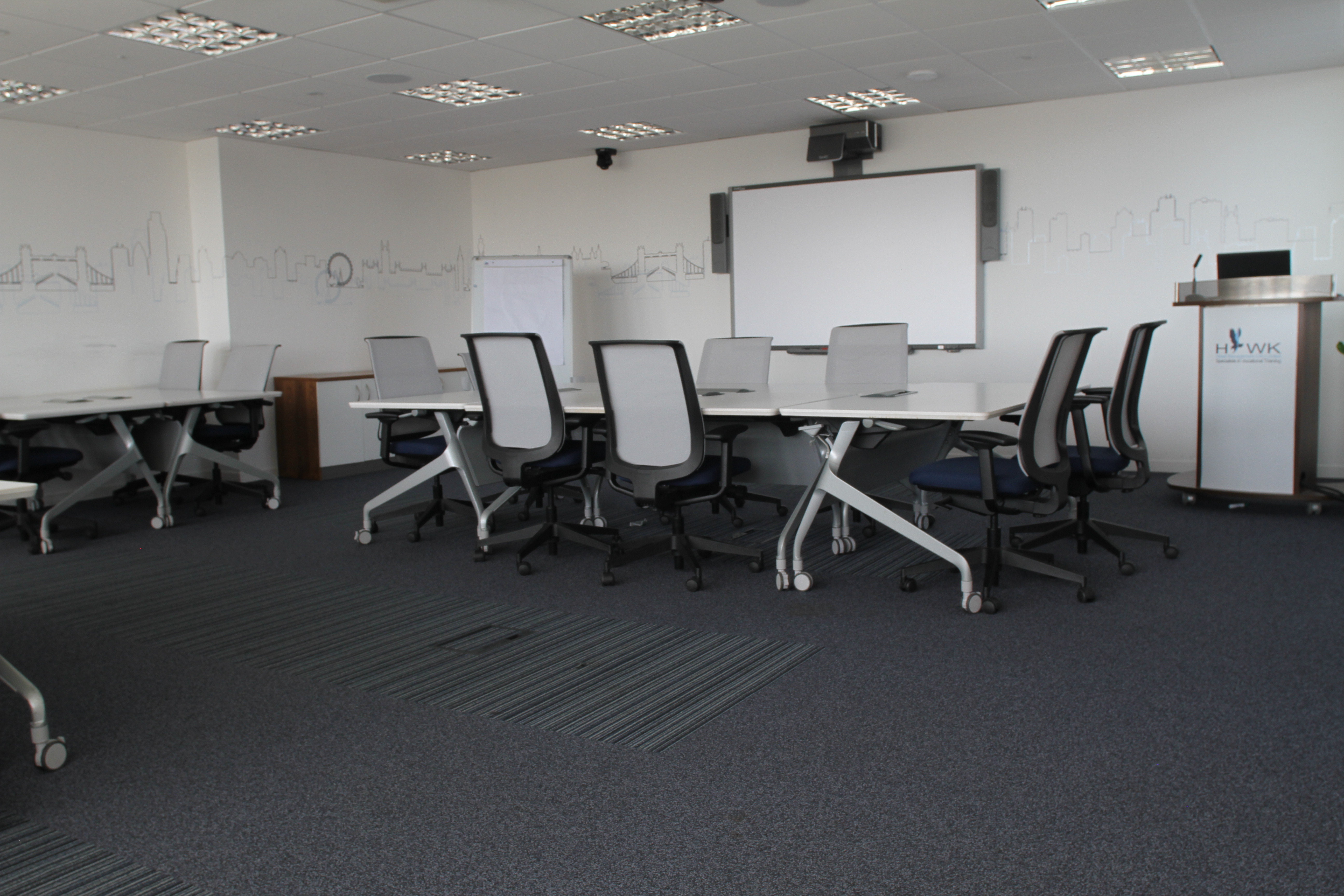 Modern meeting room in Hawk Training Studios with flexible tables and ergonomic chairs.