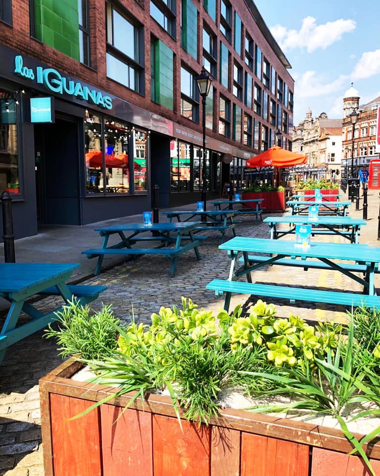 Outdoor venue at Las Iguanas Leeds with blue picnic tables, perfect for summer gatherings.