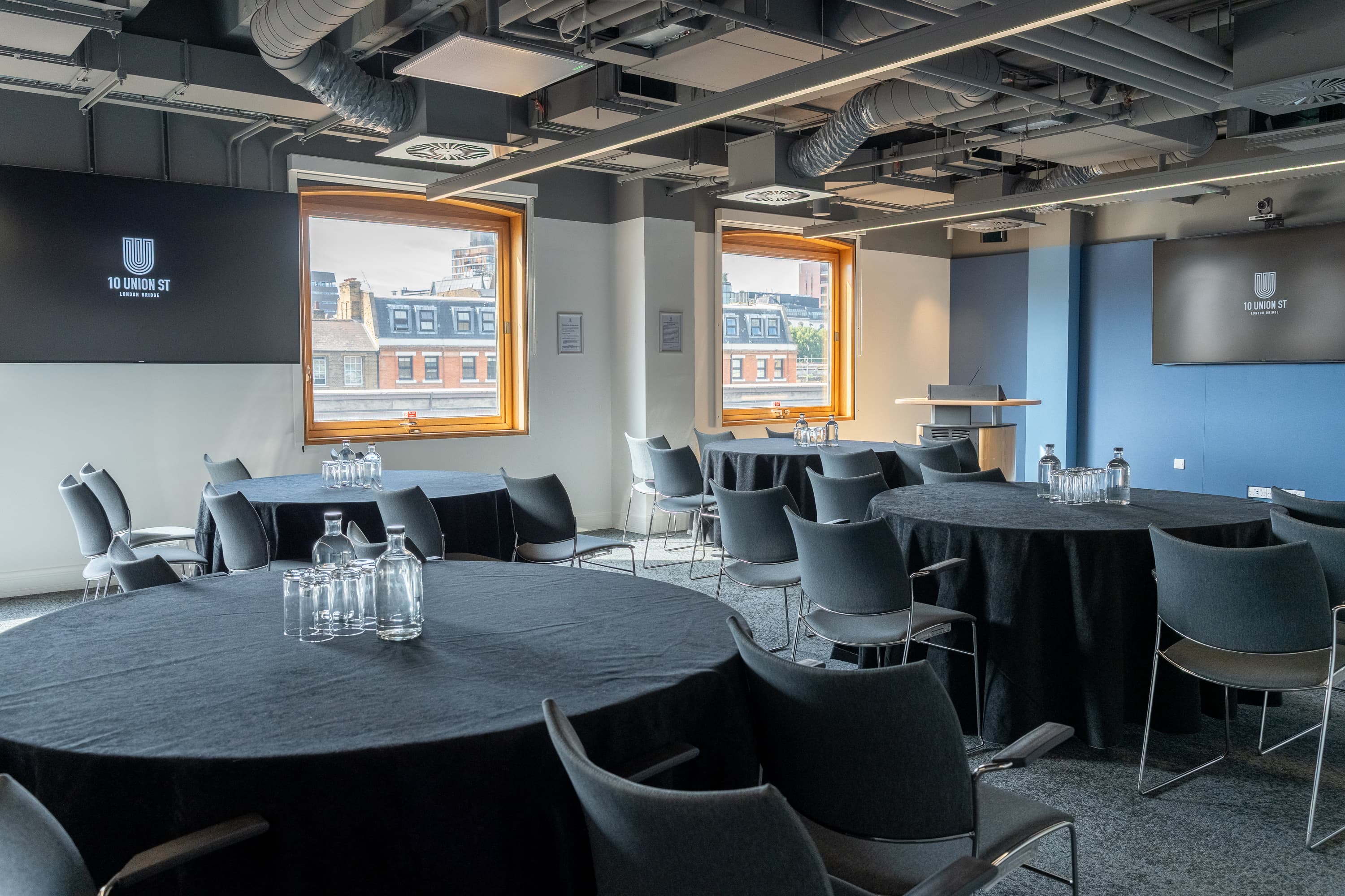 Industrial-chic breakout space with circular tables for hybrid workshops and group collaboration.