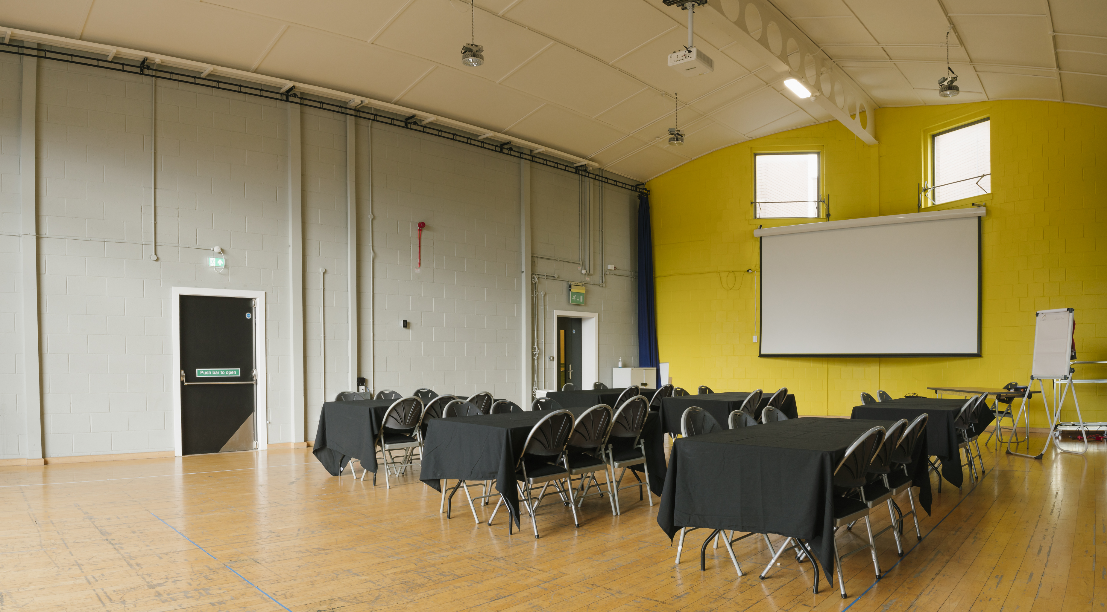 Versatile meeting space in Contact Theatre with bright yellow wall, ideal for workshops.