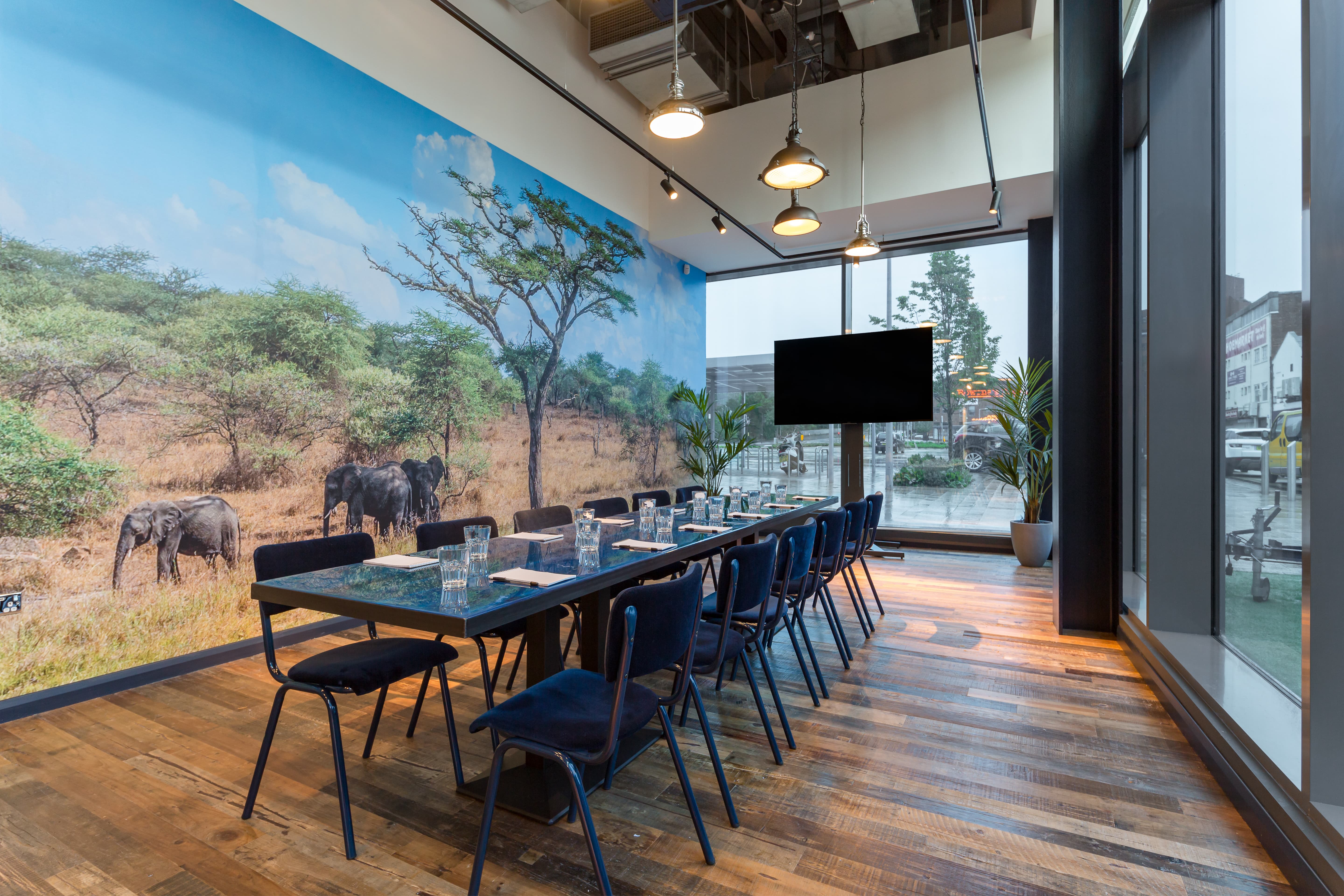 Modern meeting room with elephant mural, perfect for brainstorming and workshops.