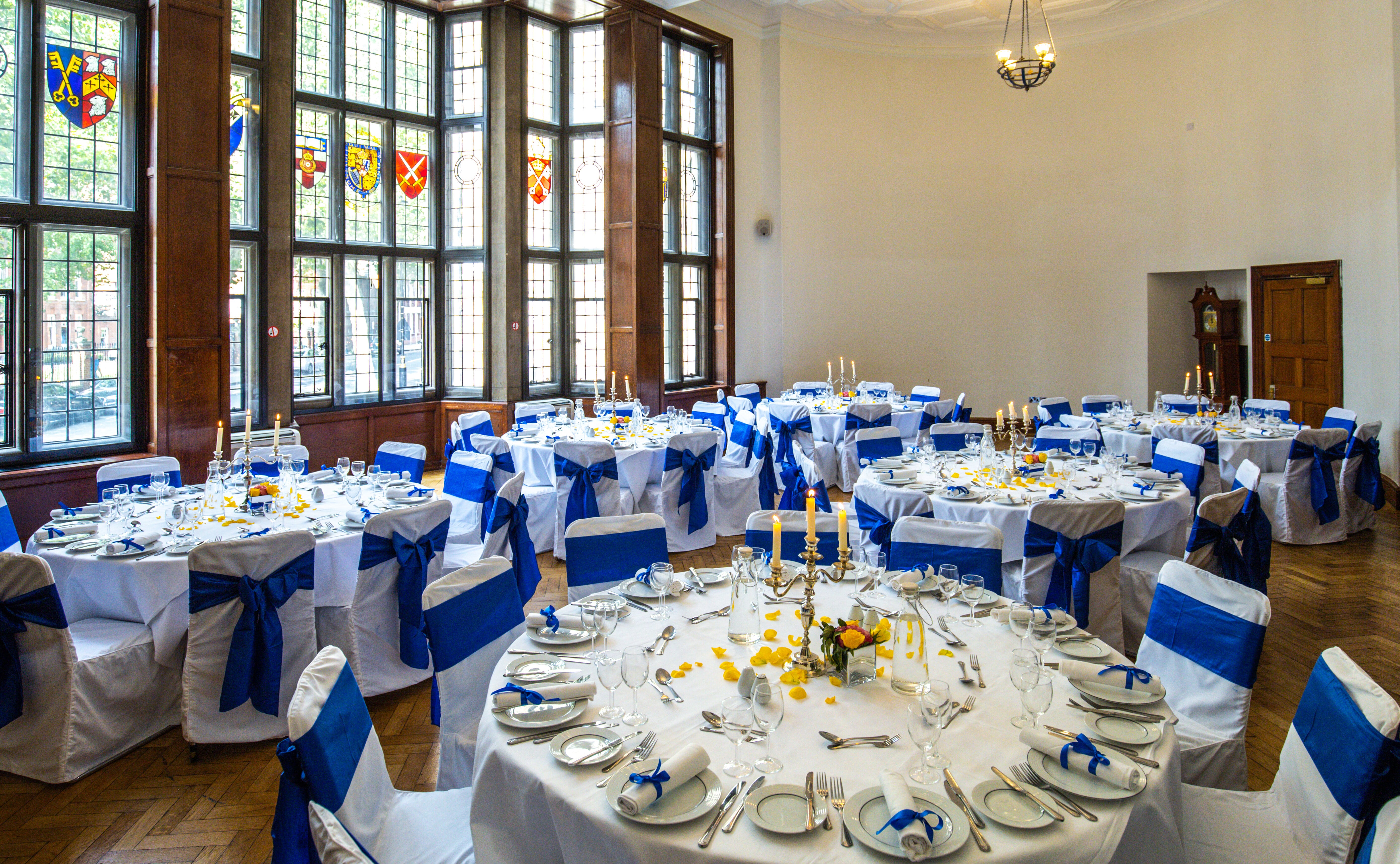 Elegant banquet hall with white linens and blue sashes, ideal for weddings and corporate events.