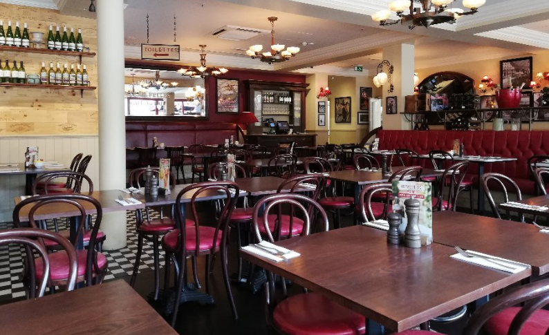 Spacious Café Rouge London venue with red leather seating for events and gatherings.