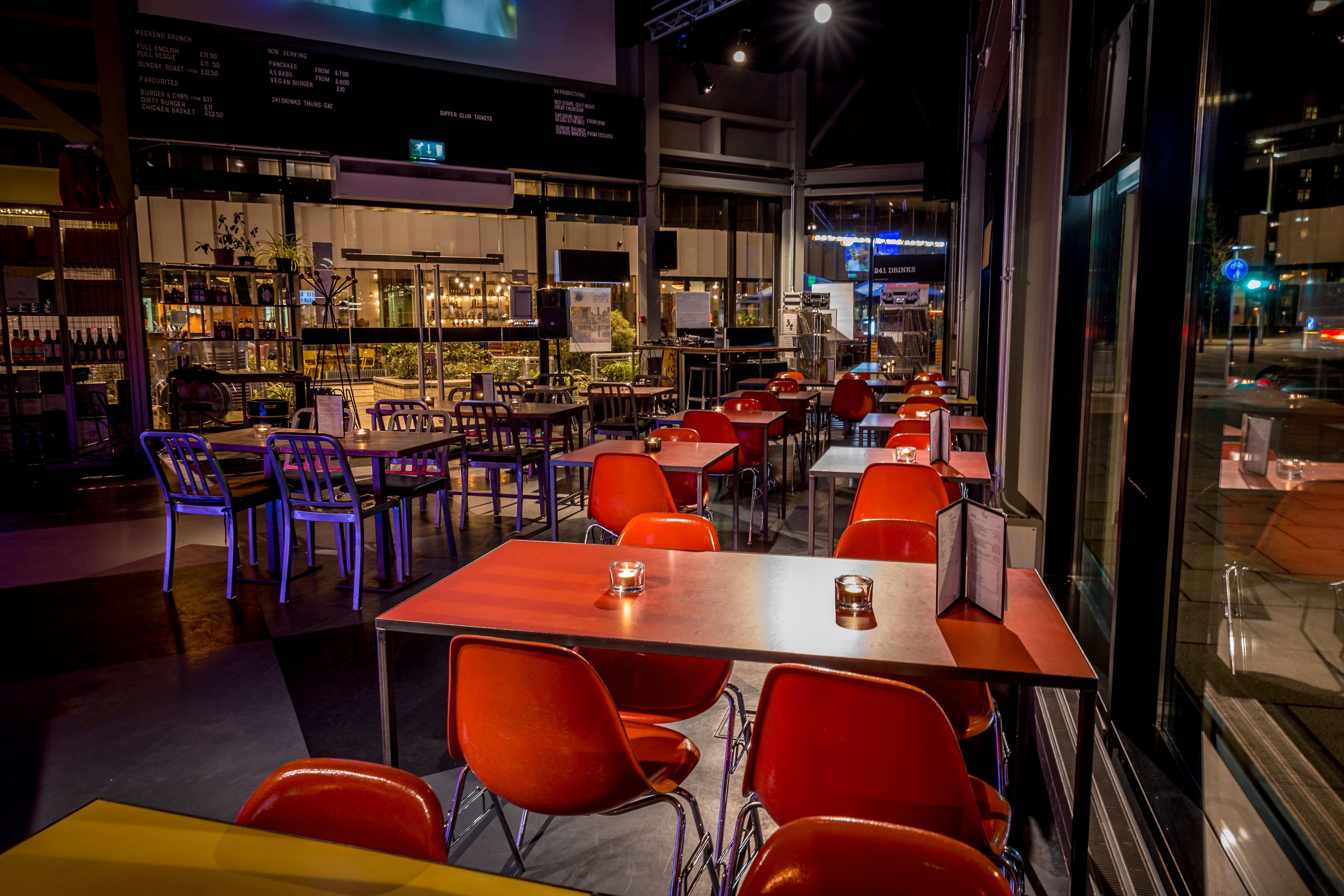 Modern event space in Village Vanguard with red chairs, perfect for networking events.