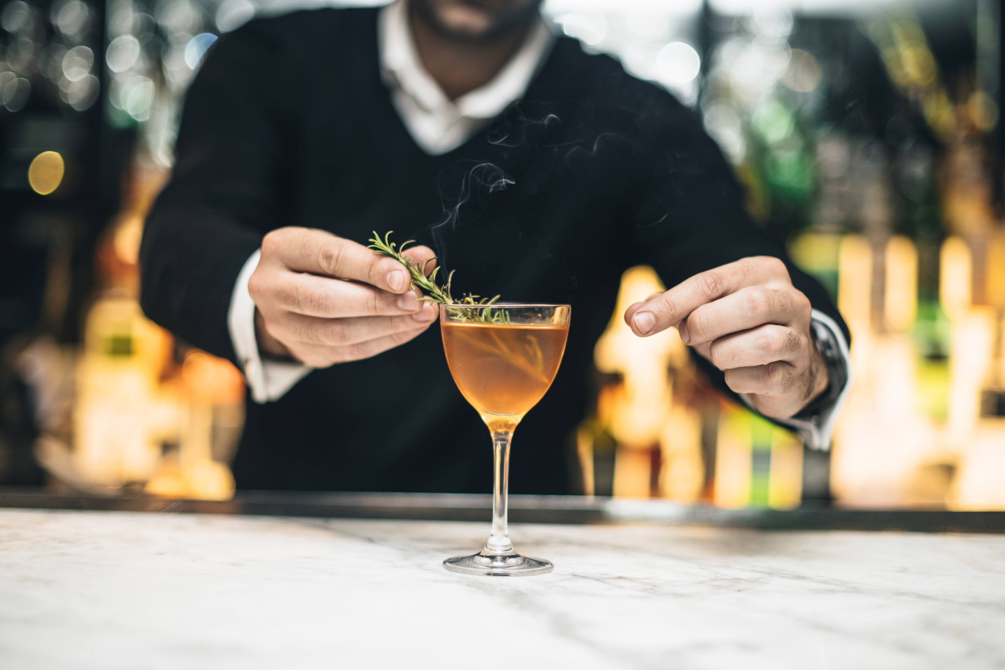Bartender garnishing cocktail at The Glasshouse Bar & Terrace, event catering excellence.