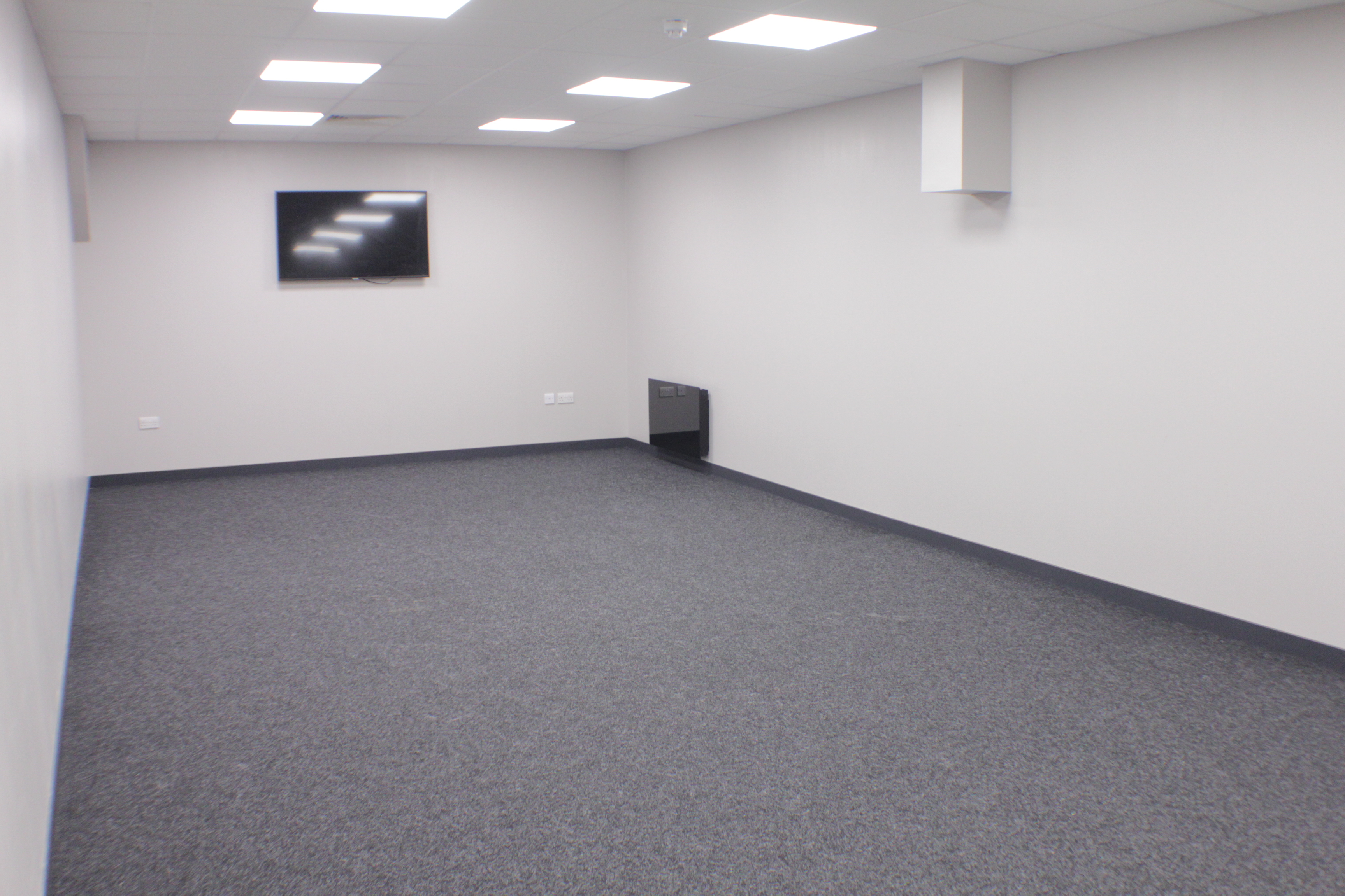 Blank meeting room with wall-mounted TV, perfect for workshops and presentations.