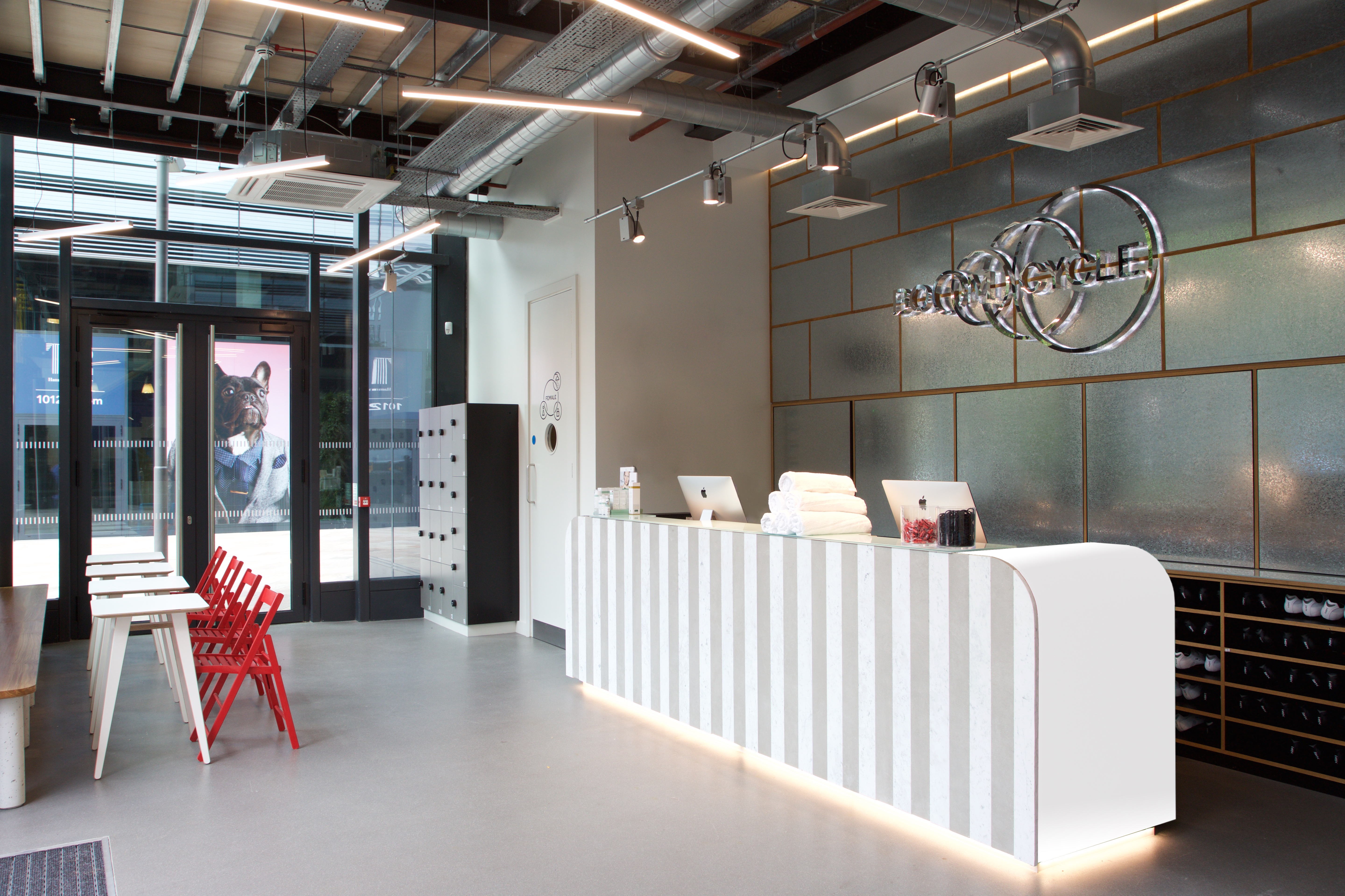 Modern reception area with white desk and red chairs for events at Boom Cycle Hammersmith.
