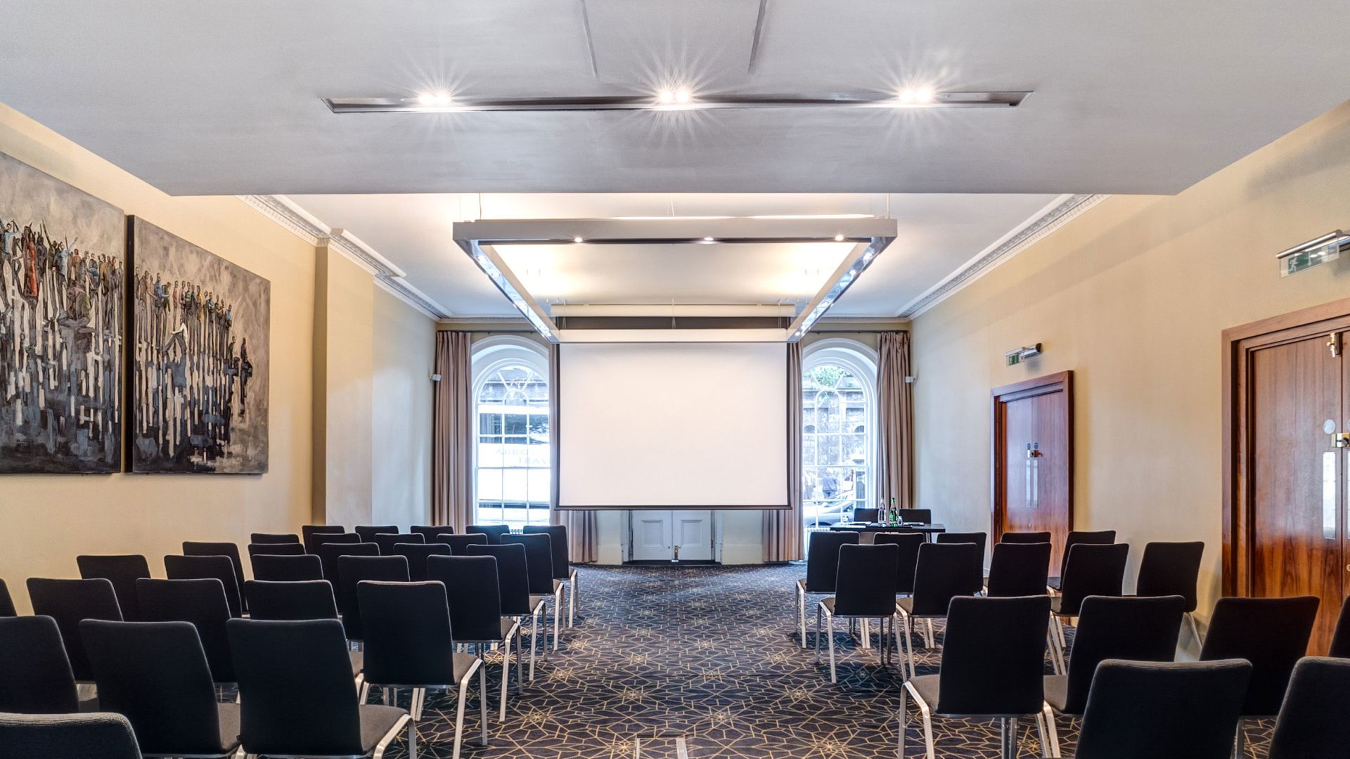 Waterloo Suite conference room with black chairs and projection screen, ideal for meetings.